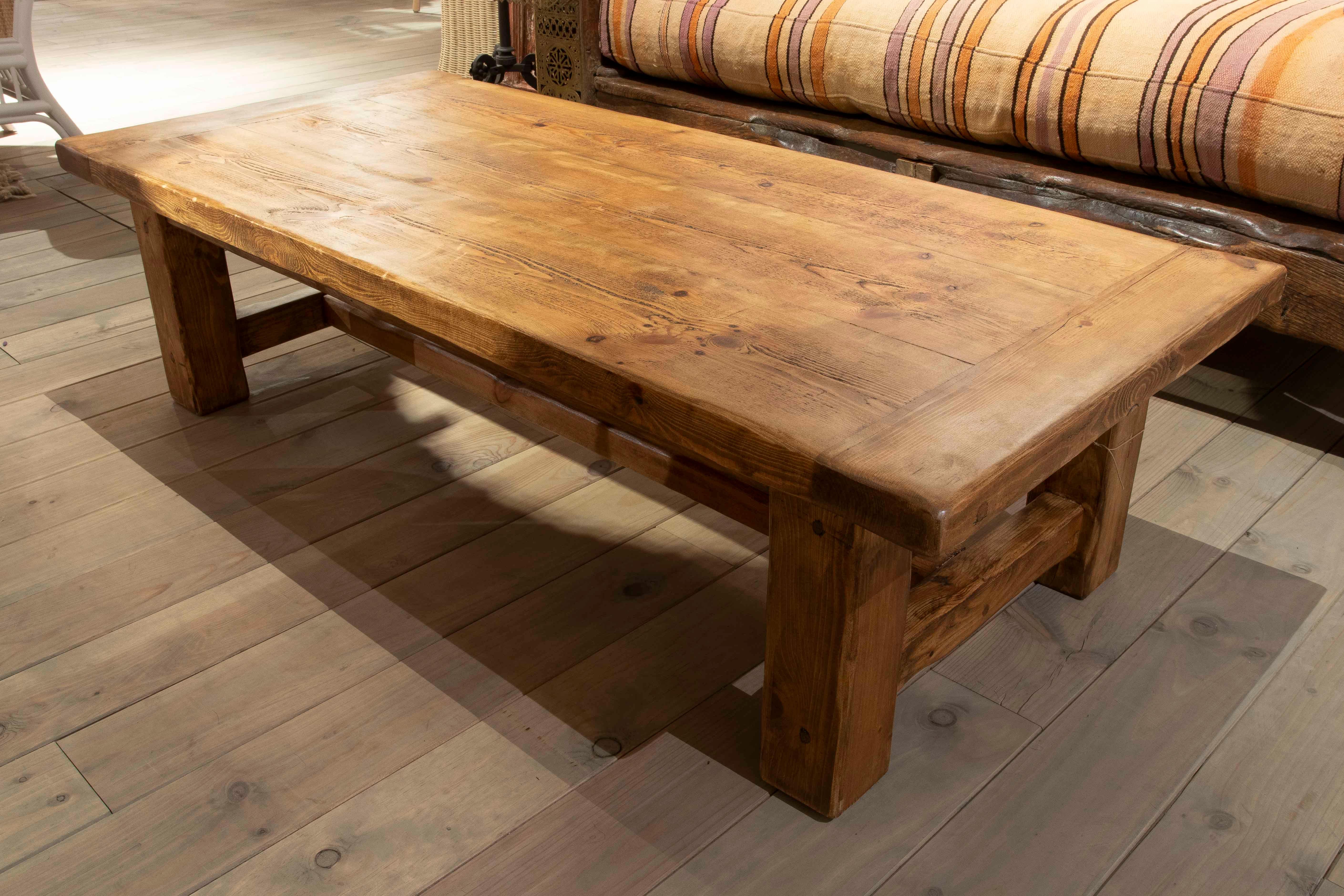 Rectangular coffee table crafted from solid wood, with a sturdy design and clean lines that emphasize its functional and timeless character. The surface features a natural finish that highlights the wood's grain and knots, bringing warmth and