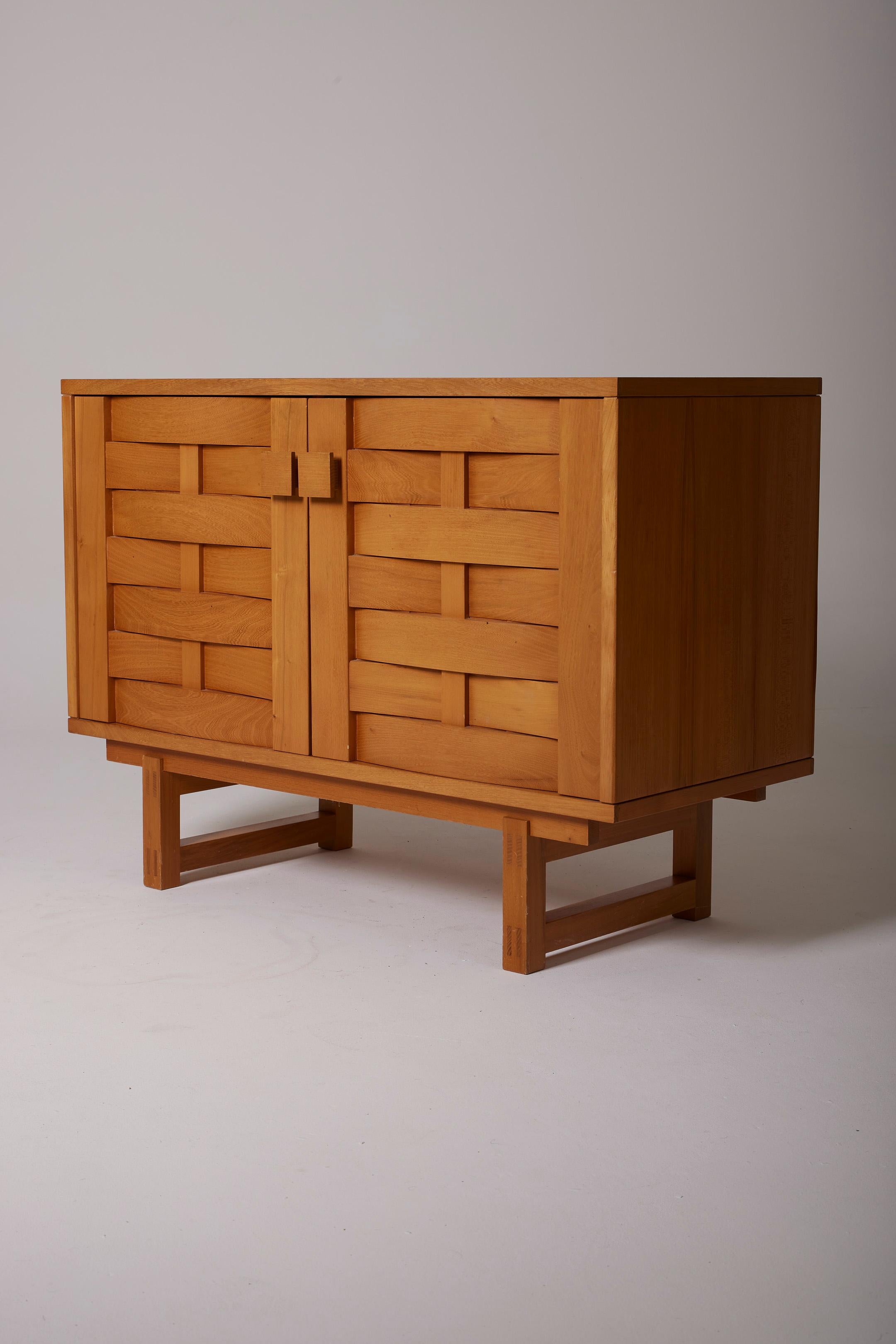 Solid ash brutalist sideboard dating from the 1960s-1970s. This sideboard features 2 swinging doors on the front with carved wood, opening to reveal 2 compartments, each with a shelf.
LP3032