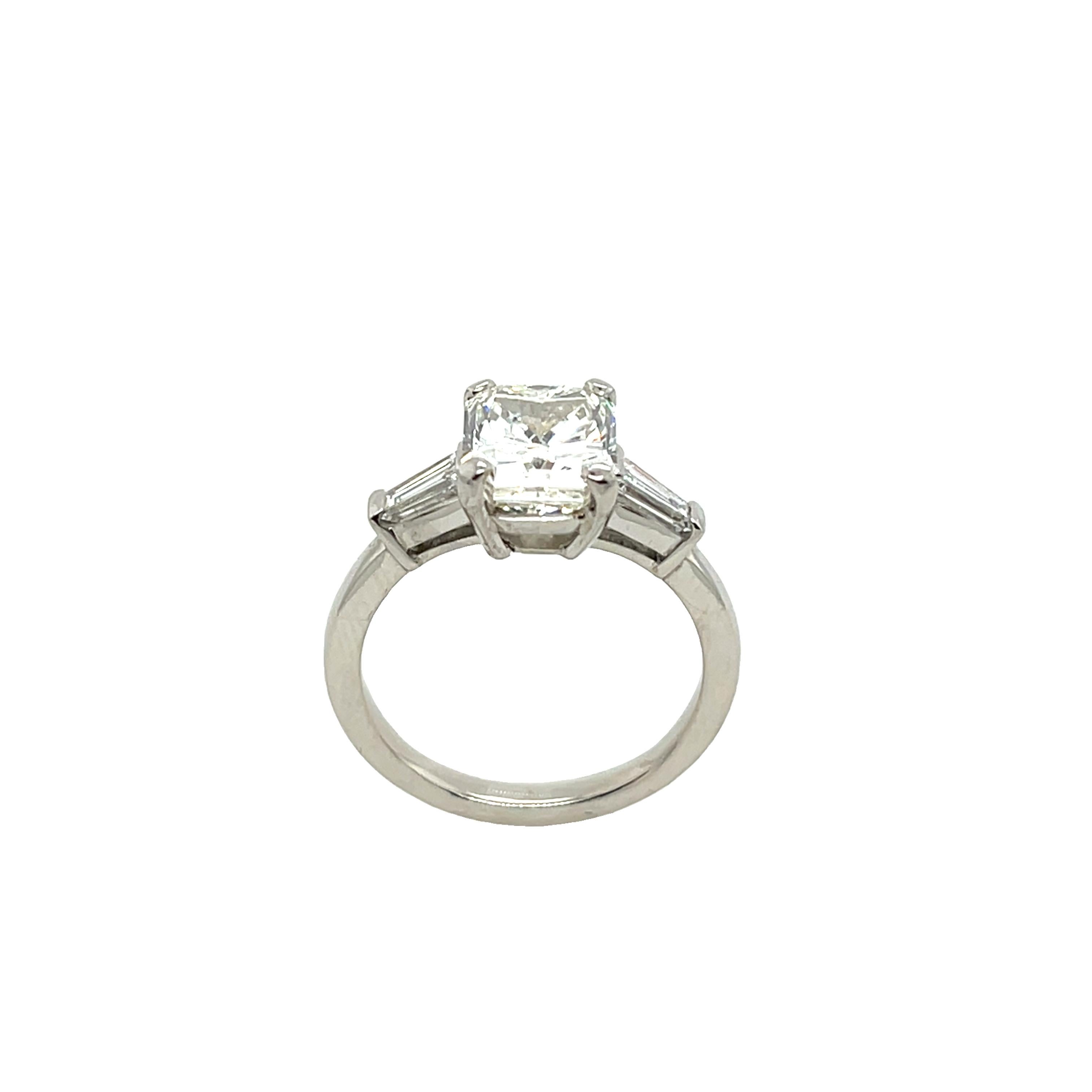 Une bague de fiançailles solitaire intemporelle et élégante, 
mettant en valeur un magnifique diamant de 2,47ct J/VS2 de taille radiant, 
flanqué de diamants baguettes effilés sur chaque épaule. 
Magnifiquement serti en or blanc classique de 18 ct,