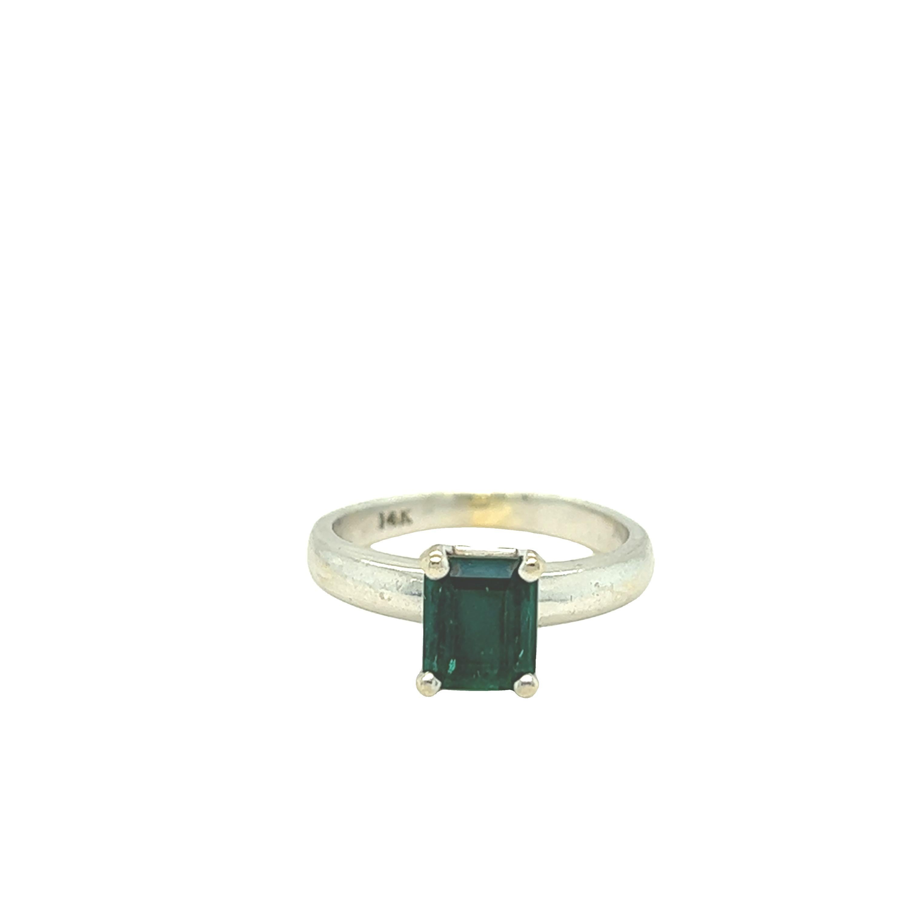 Simple and elegant vintage solitaire ring features a natural deep green emerald cut emerald. The center stone weighs approximately 1.30 carat and is set in four prong setting 14k white gold. Size 5 and can be resized.

Gemstone: Emerald
Cut: Emerald