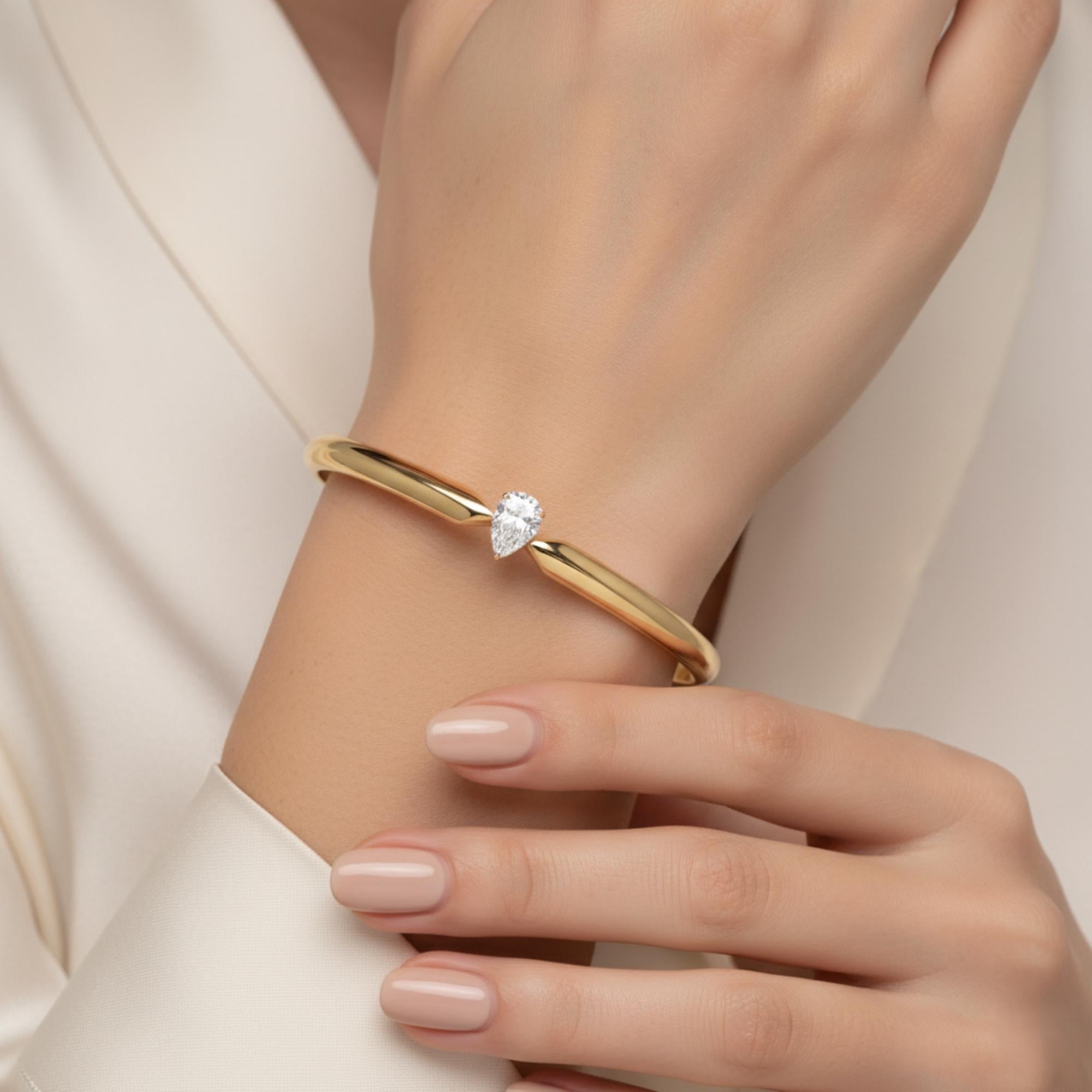 Solitaire Pear Cut 0.51Ct Certified Diamond Cuff Bracelet 14k Yellow Gold
This exquisite 18k gold bangle, crafted with a sleek, modern silhouette and highlighted by a stunning pear-cut natural diamond at its center. The minimalist design features