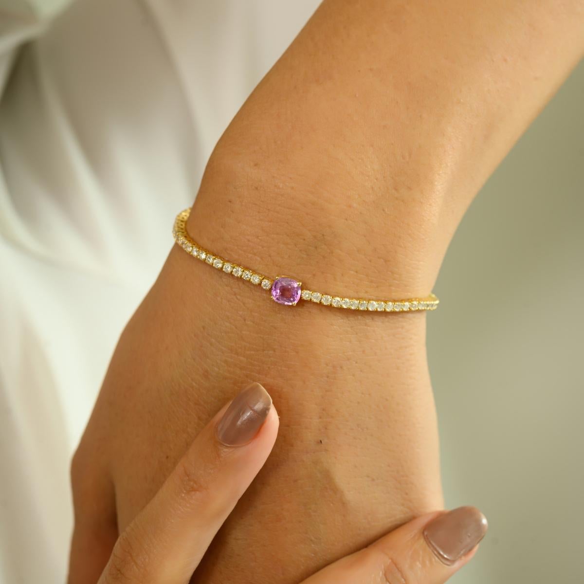 Delicately crafted in 14K yellow gold, this exquisite bracelet features a stunning 0.74 carat cushion-cut pink sapphire at its center, radiating charm and femininity. Framed by a brilliant array of 1.97 carats of sparkling diamonds, the design