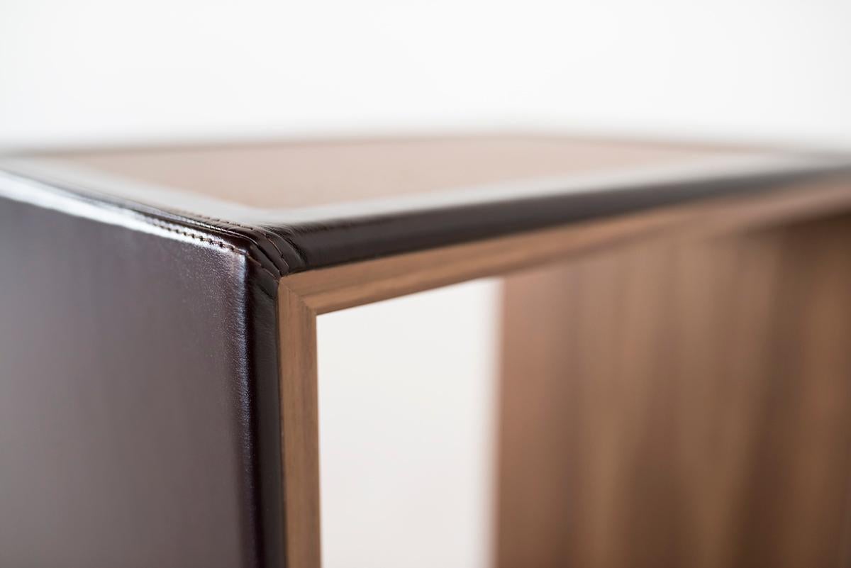 Solo is a side table supported by brass legs which raise the element slightly from the floor while conferring a light accent. It is devoid of any back panel so that its contents may be easily accessed from either side, and its upper surface is