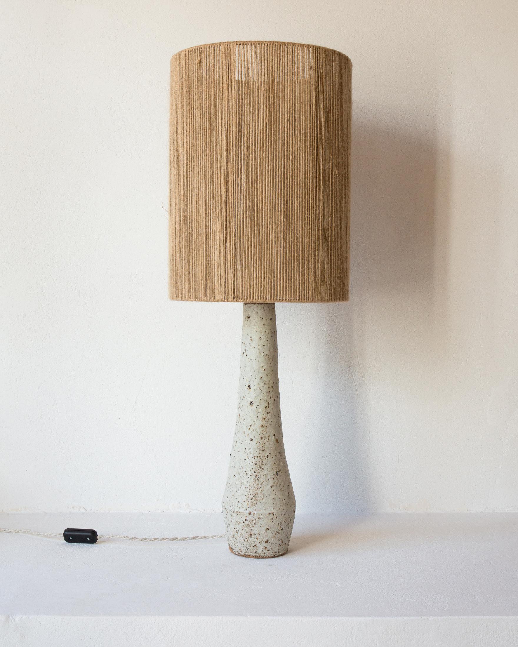 Solstice Matt Speckled Grey Textured Ceramic Table Lamp by Grès Éditions
Unique Piece.
Dimensions: Lampshade: Ø 30 x H 40 cm.
Base: H 42 cm.
Materials: Jute and ceramic.
Weight: 3 kg.

Electrical system: linen woven electric cable (length: 150 cm),