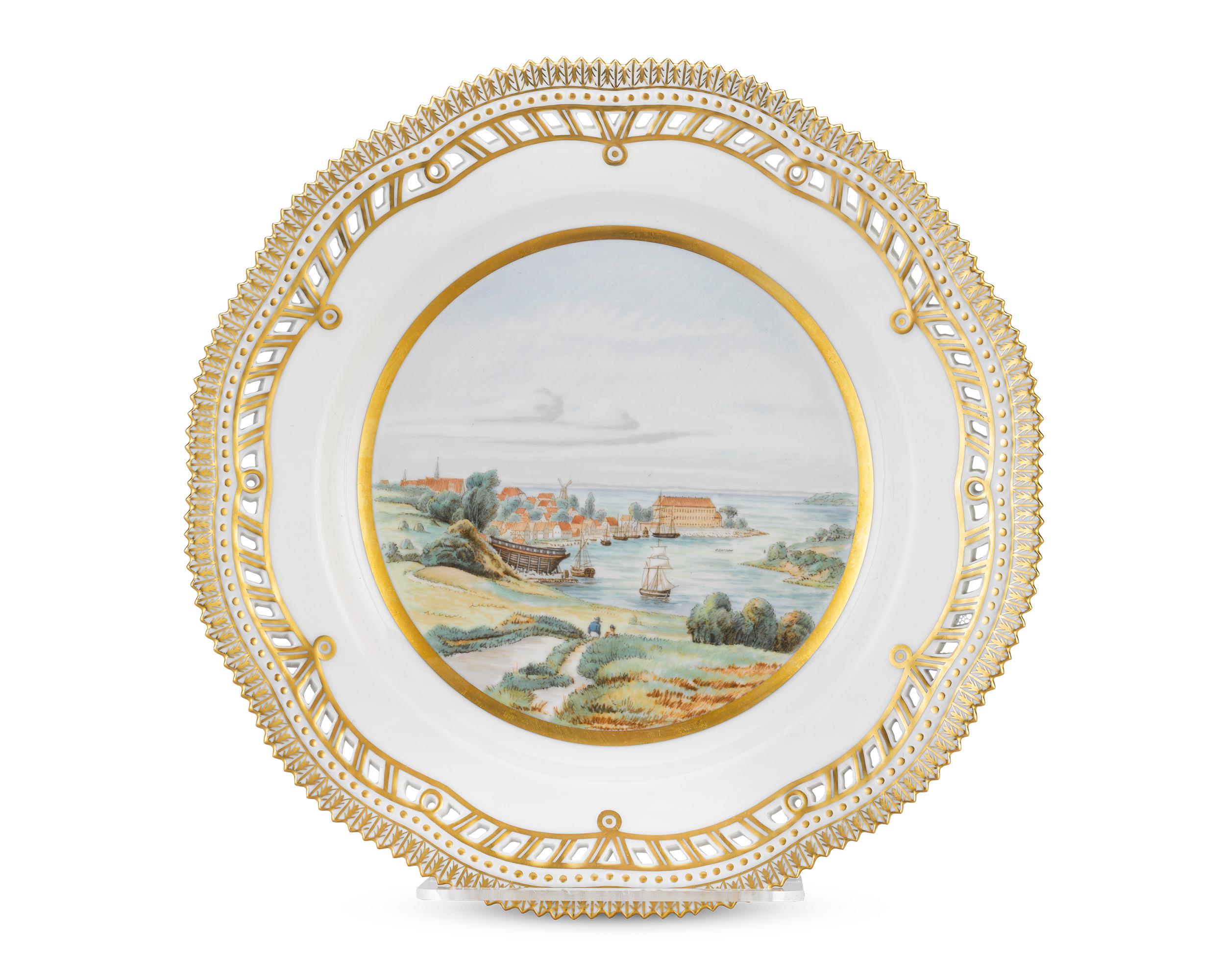Dieser Teller der berühmten Porzellanmanufaktur Royal Copenhagen zeigt eine wunderbar detaillierte Seelandschaft mit Schiffen und einem malerischen dänischen Dorf, das das Schloss Sonderborg umgibt. Zusätzliche vergoldete Verzierungen und ein zart