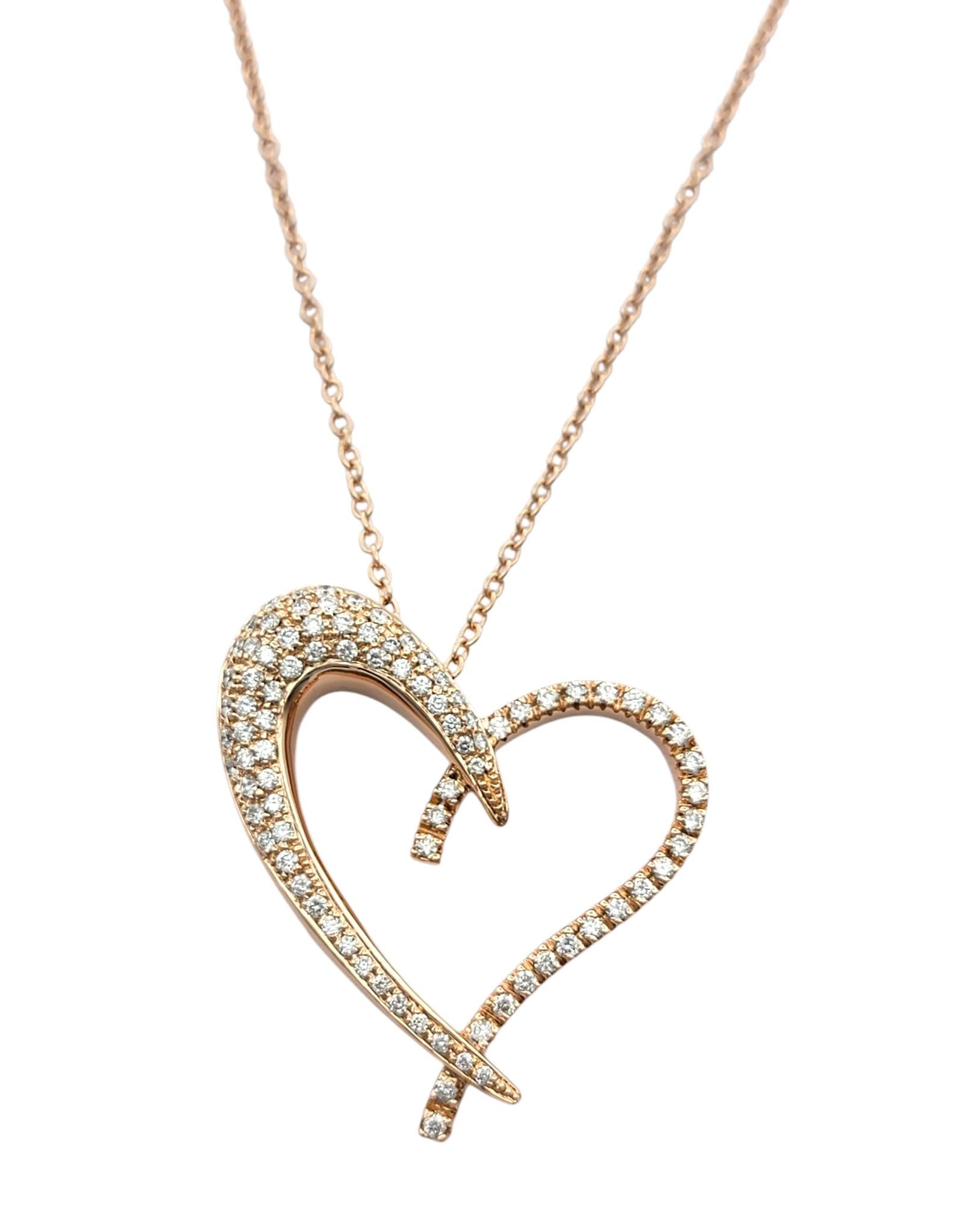 Réalisé en or rose 14 carats, ce collier à pendentif cœur ouvert Sonia B. présente une silhouette douce et romantique ornée de diamants sertis en pavé. Le cœur s'incurve doucement, avec un côté plus prononcé, créant une asymétrie élégante qui ajoute