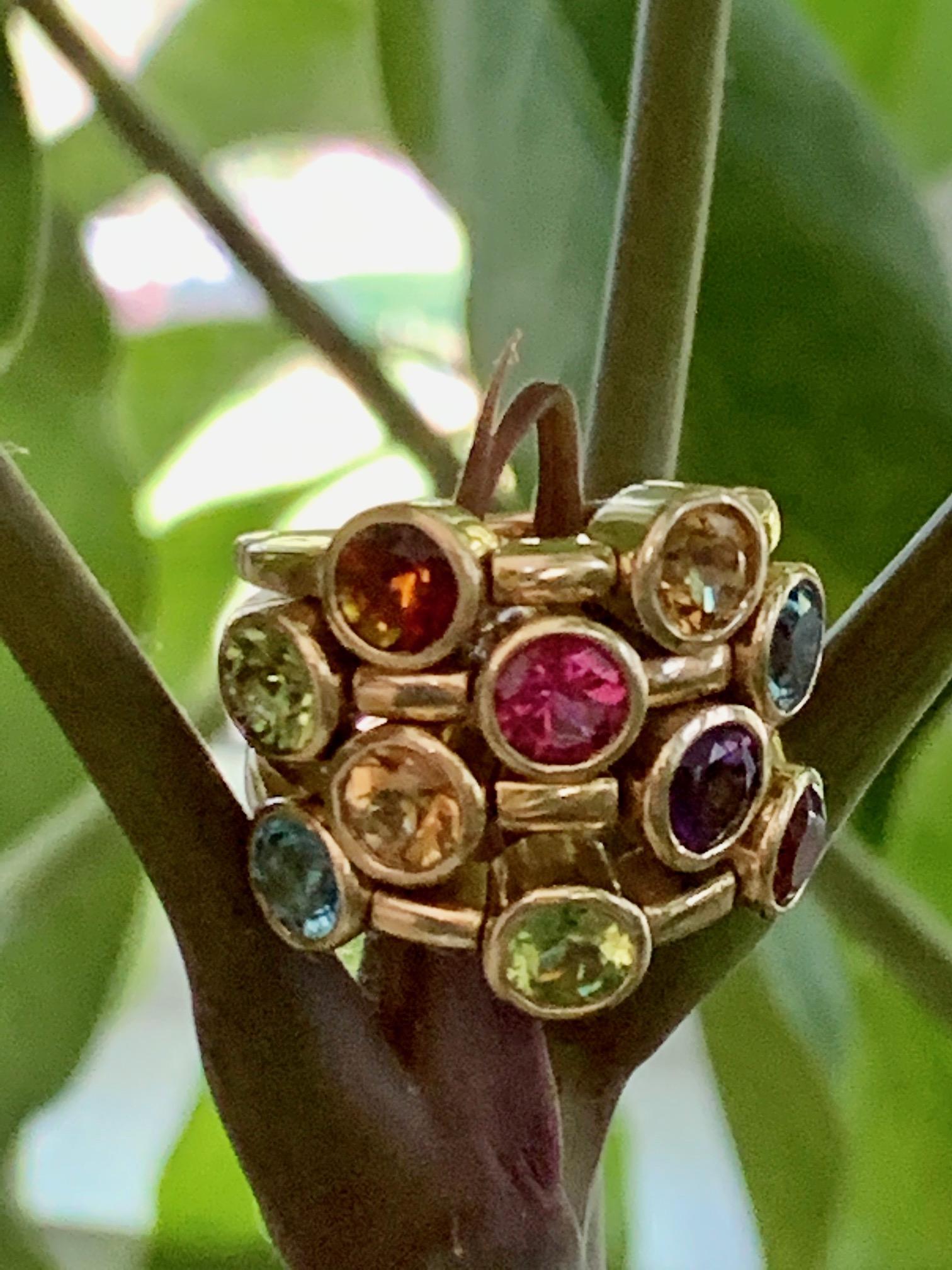 This is a modern, designer, 14 Kart yellow gold ring designed by Sonia B.  

The ring features:
10 round faceted colored gem stones = 5mm each
Includes: Peridot, Blue Topaz, Pink Tourmaline, Citrine and Amethyst
Each row of stones, moves up and