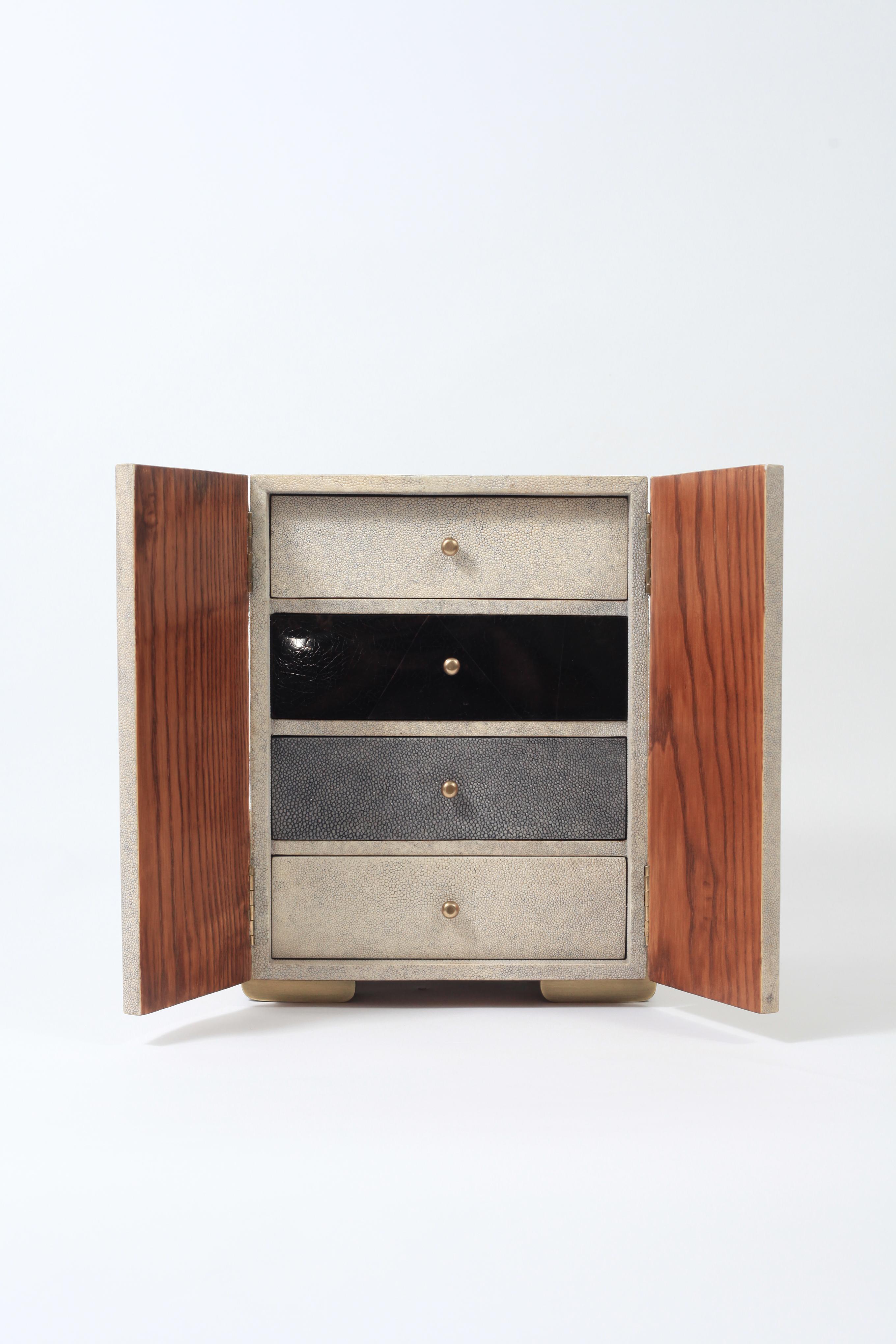 The Sonia jewelry chest in cream shagreen, shell and brass by R&Y Augousti is a stunning piece to store your personal items. This piece has 2 doors that open to 4 drawer compartments, inlaid in a mixture of cream shagreen/black shell and grey blue