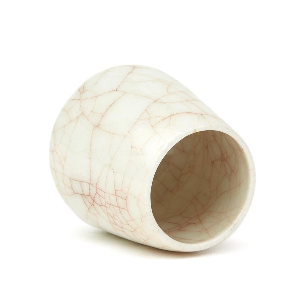 A stunning studio ceramic porcelain squat shaped miniature rounded vase decorated in a brown stained craquelure glazed finish on a white ground by renowned Cambridgeshire based potter Sonia Lewis. This finely and lightly made example stands on a