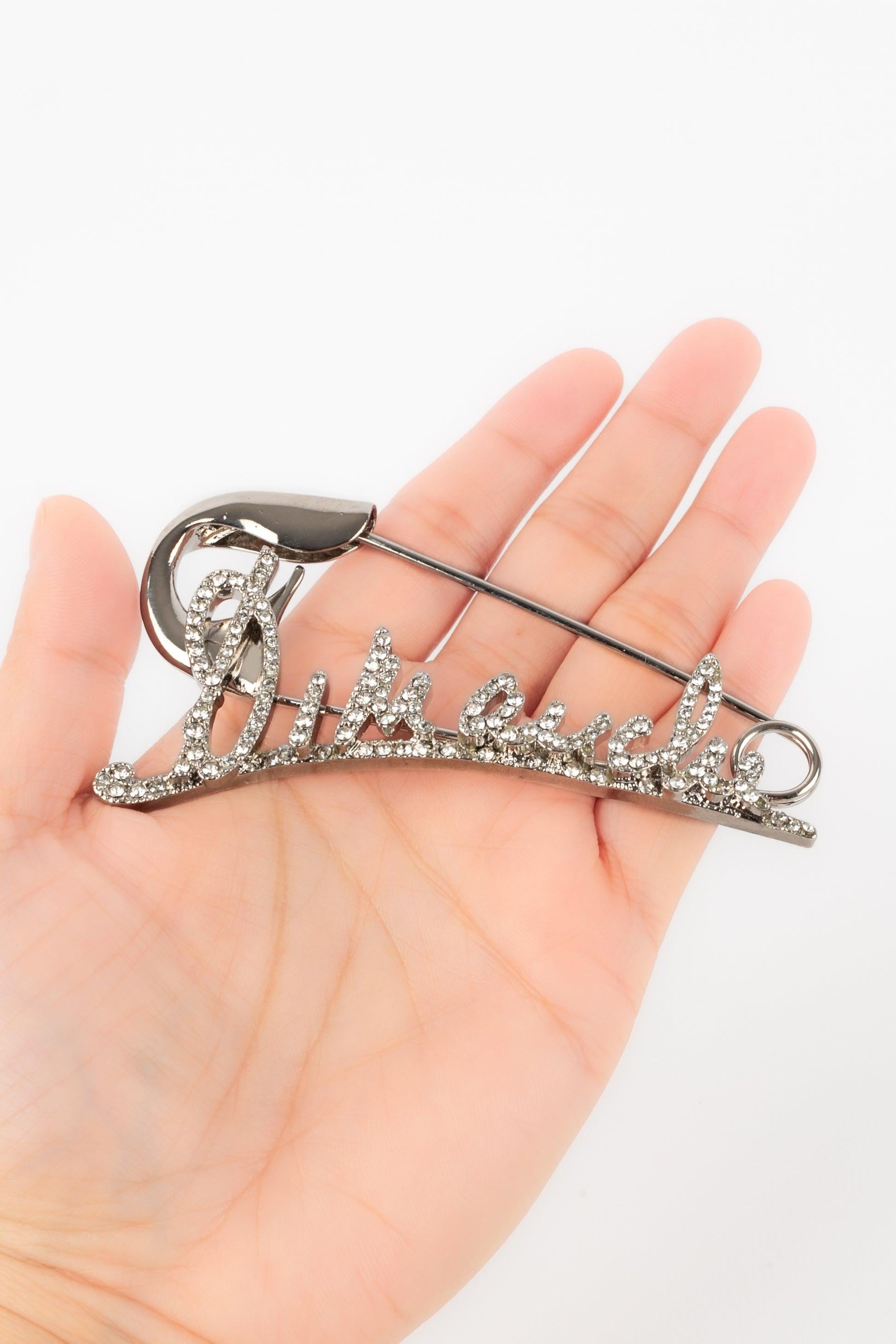 Sonia Rykiel - (Made in France) Silvery metal brooch ornamented with rhinestones and representing the word 'Dimanche' ('Sunday').

Additional information:
Condition: Very good condition
Dimensions: 9.5 cm x 5 cm

Seller Reference: BR193