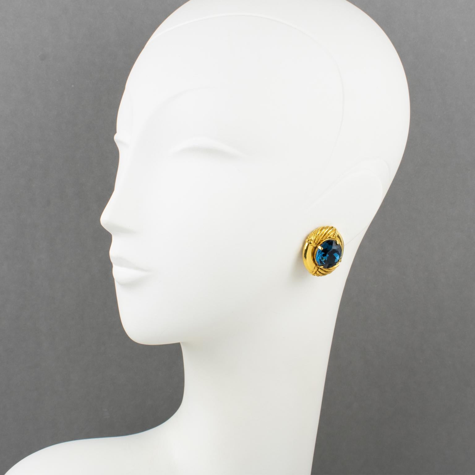 This is a remarkable pair of clip-on earrings designed by the renowned fashion house Sonia Rykiel Paris. These earrings flaunt a stunning gilt metal domed shape, boasting a textured top that showcases a large and captivating cobalt blue crystal