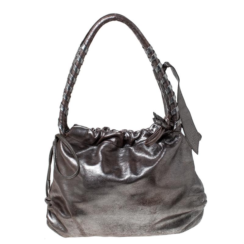 Flaunt your fashion quotient by adorning this top-class handbag from Sonia Rykiel. This leather bag is brilliantly fashioned in keeping with trends. Lined with fabric, the interior of this bag is spacious. The silver bag features dual handles and