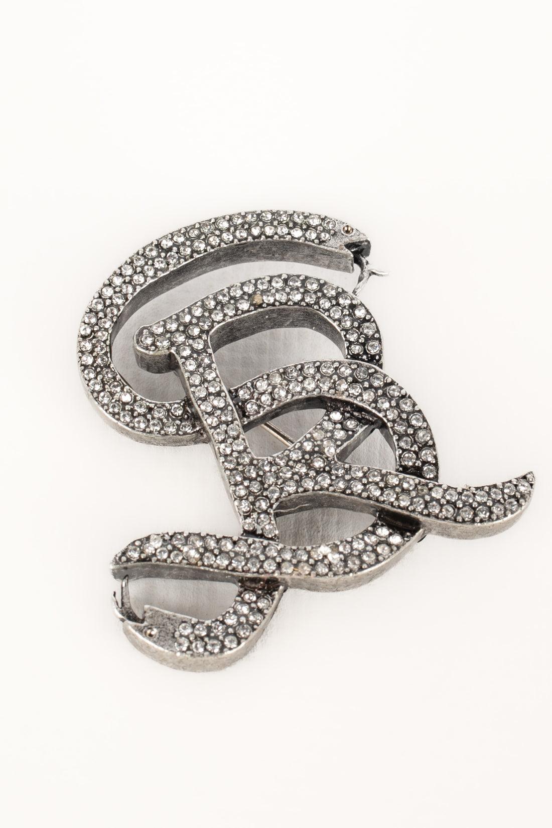 Sonia Rykiel - (Made in France) Silvery metal brooch with rhinestones representing a snake coiled on an R.

Additional information:
Condition: Very good condition
Dimensions: 4 cm x 3.3 cm

Seller Reference: BR190
