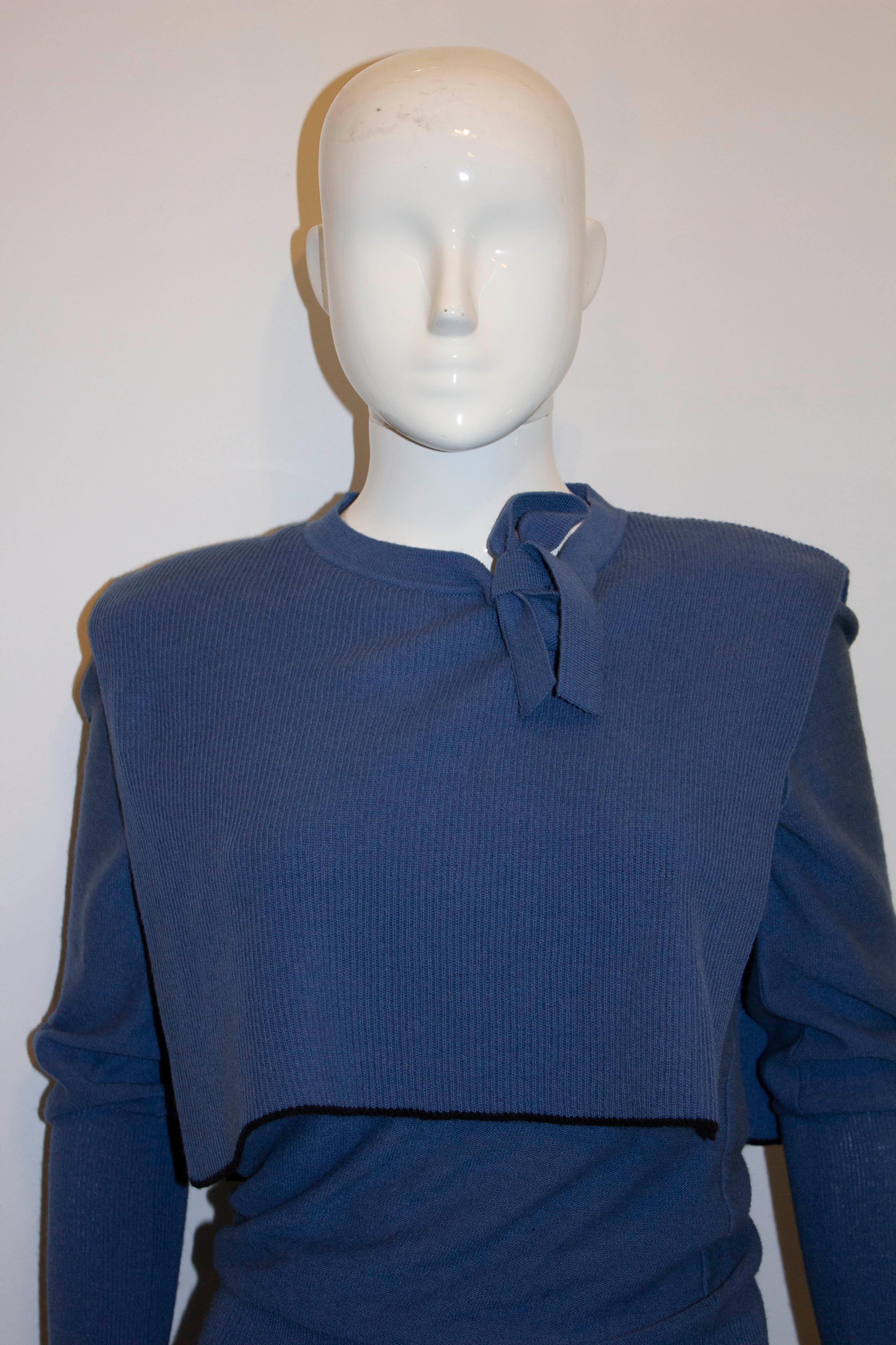 A head turning vintage jumper by Sonia Rykiel.  The jumper is in a sky blue colour with attached bib detail . The jumper has wide rib detail on the cuffs and hem and a self fabric tie bow and small knitted shoulder pads. Size 36 Bust up to 35'',
