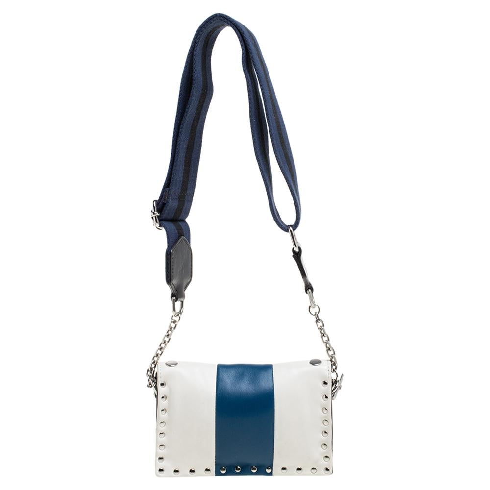 Swap that everyday tote with this charming crossbody bag from the house of Sonia Rykiel. It features a white leather body with a touch of blue, an adjustable shoulder strap, and metal studs. The Alcantara interior can hold your daily essentials with