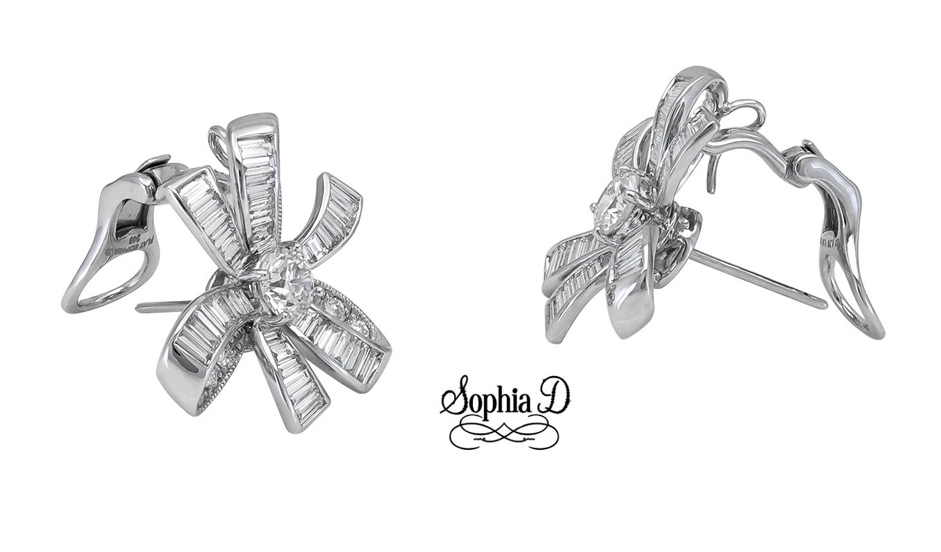 These ribbon-style diamond earrings by Sophia D. feature a stunning design that showcases two center round diamonds totaling 1.14 ct. Accentuating their brilliance are baguette-cut diamonds, adding an impressive 2.26 ct. Crafted in platinum, these