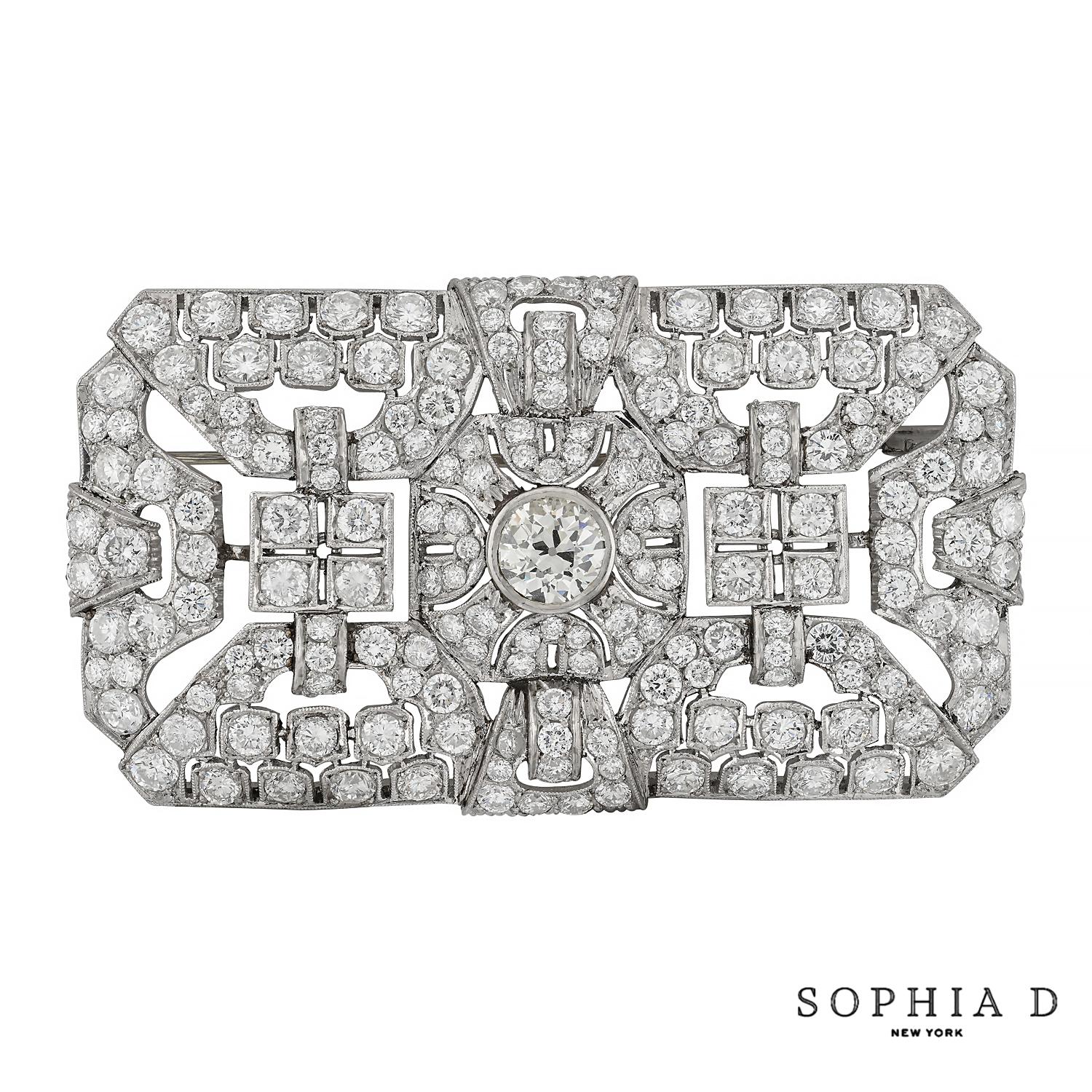 This striking brooch showcases an Art Deco design, featuring a central round diamond of 1.20 carats set in a platinum setting. Surrounding this focal point is an impressive array of diamonds totaling 11.61 carats, meticulously arranged to highlight