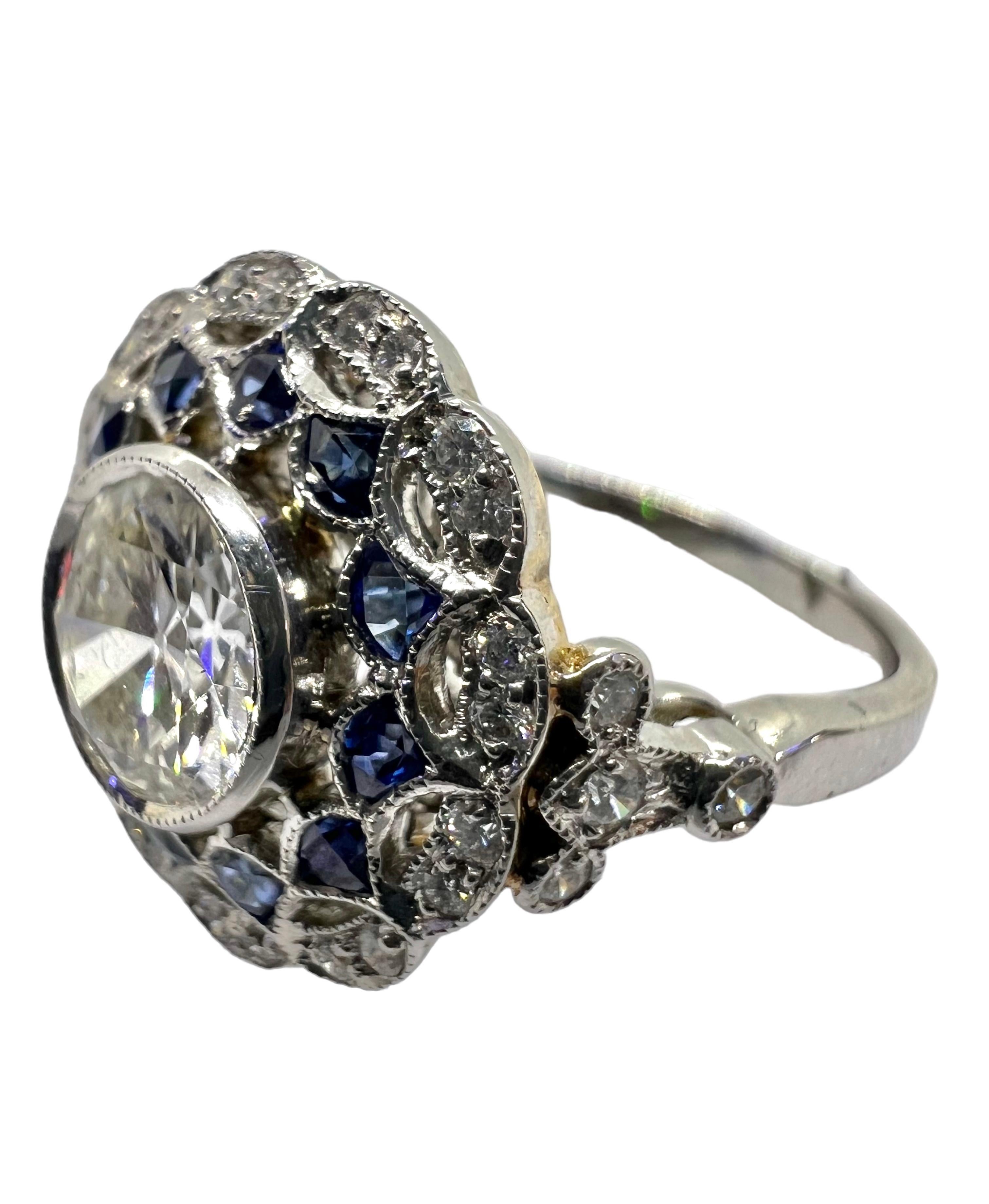 Platinum ring that features a .89 carat center round diamond, .91 carat blue sapphire and .20 carat small diamonds. 

Sophia D by Joseph Dardashti LTD has been known worldwide for 35 years and are inspired by classic Art Deco design that merges with