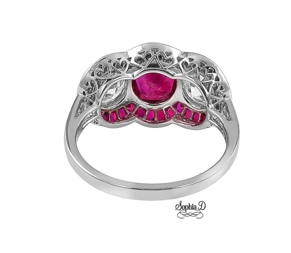 Designed by Sophia D, this three stone ring set in platinum features a round cut ruby center stone that weighs 1.91 carat, with two round diamonds on the side that weighs 0.92 carat and 0.90 carat and accentuated with small rubies that weigh 0.90