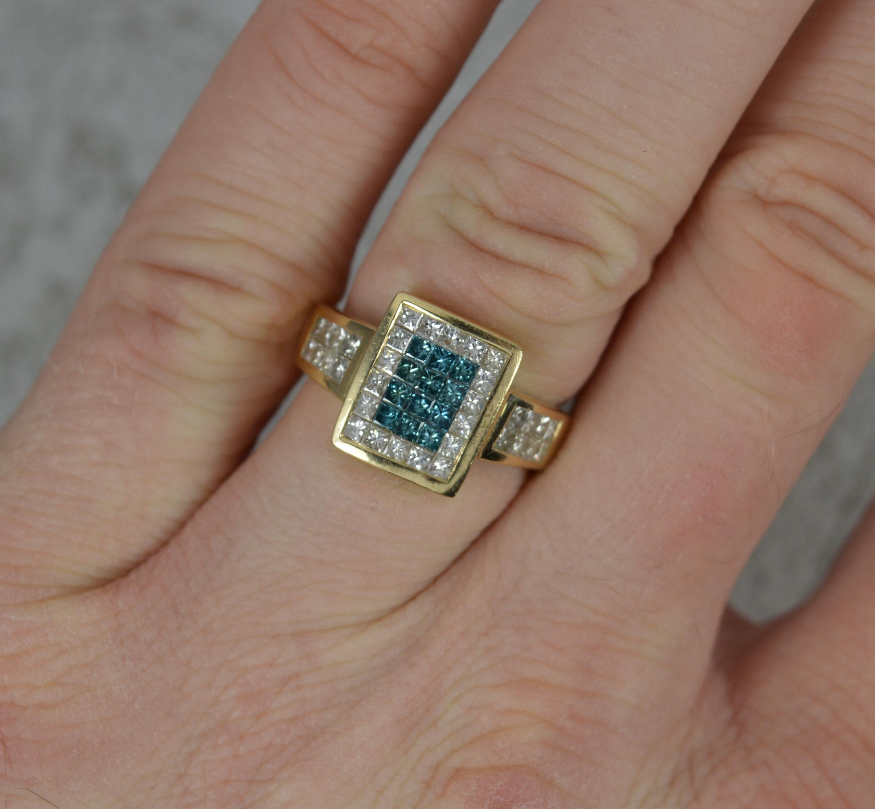 A superb designer diamond ring by Sophia Fiori. 
Solid 14 carat yellow gold example.
Designed with a rectangular panel head, 5x6 princess cut diamonds of white and blue colour with an additional 8 diamonds to each shoulder.
The 46 diamonds total