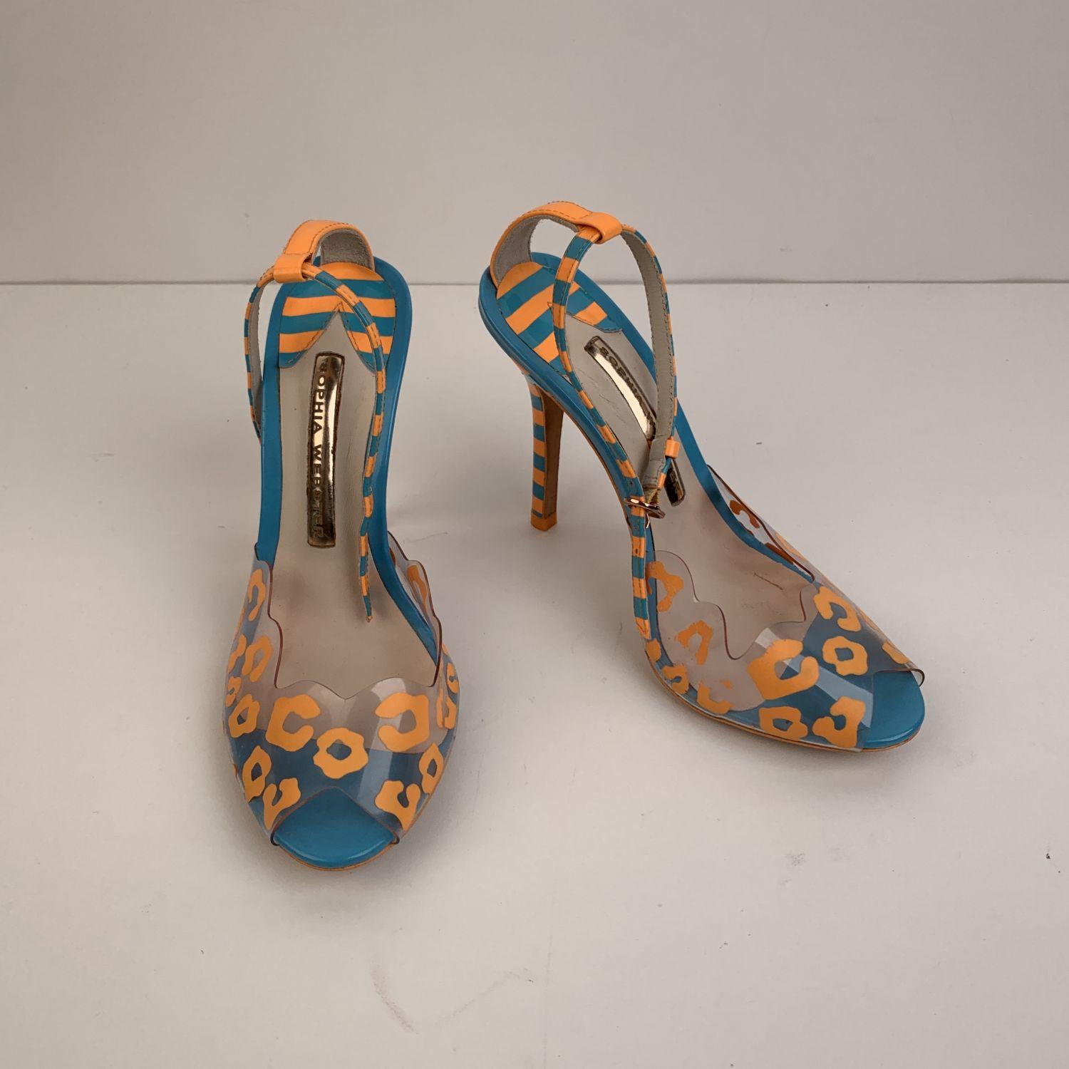 Sophia Webster open toe sandals in orange and blue colors. It features a plastic upper part with an animalier pattern, anckle strap with buckle closure and covered striped heels. Heels height: 4.25 inches - 10,8 cm. Leather insoles and outsoles.