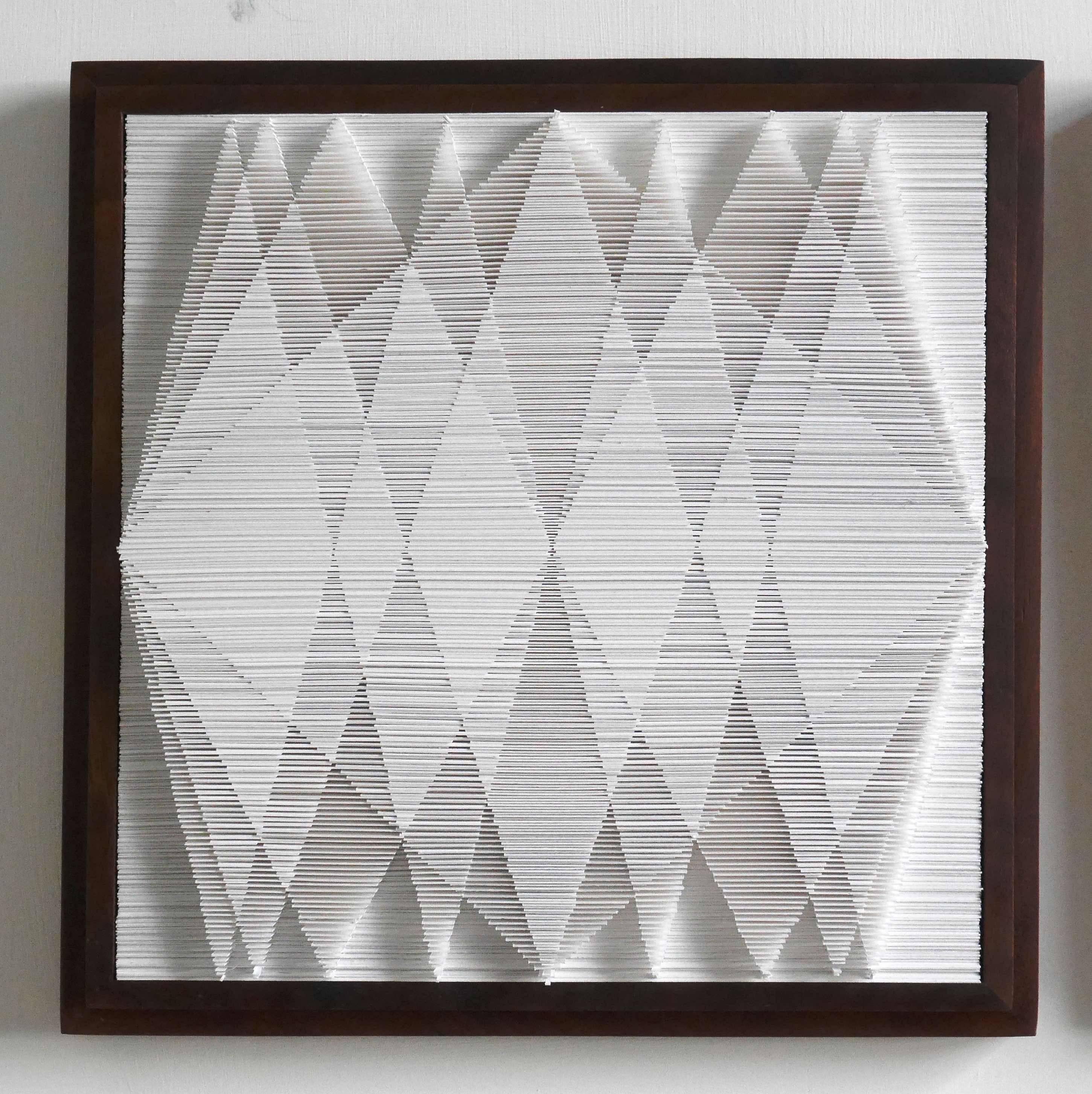 In this work, Sophie has taken the idea of stacked paper and turned it into a visual and contemplative experience.  Mounted in a wooden box frame, the cut edge of the paper forms a series of triangles that change shape as you move.

It is not