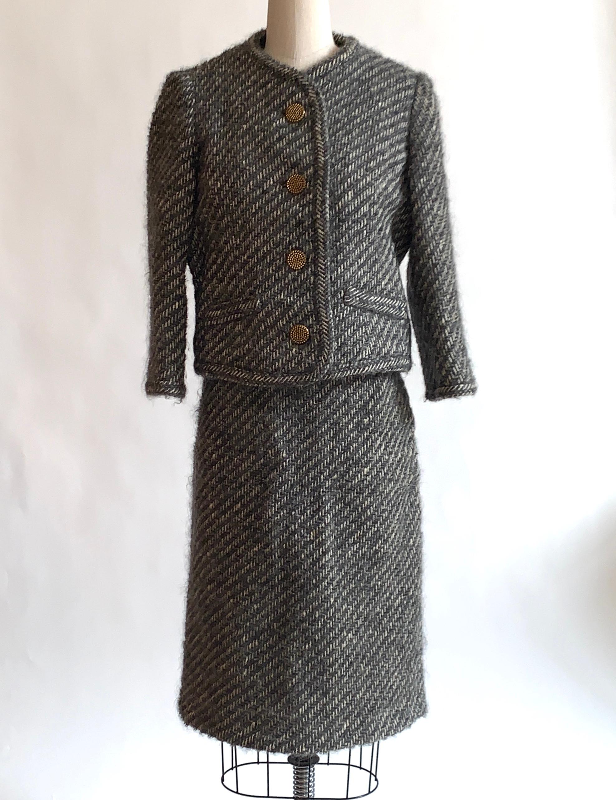 Vintage 1960s Sophie of Saks skirt suit in a super textured grey and white weave. Textured brassy colored metal buttons. Side zip and hook and loop closure at side skirt, five buttons at jacket front..

No content label, feels like it might be a