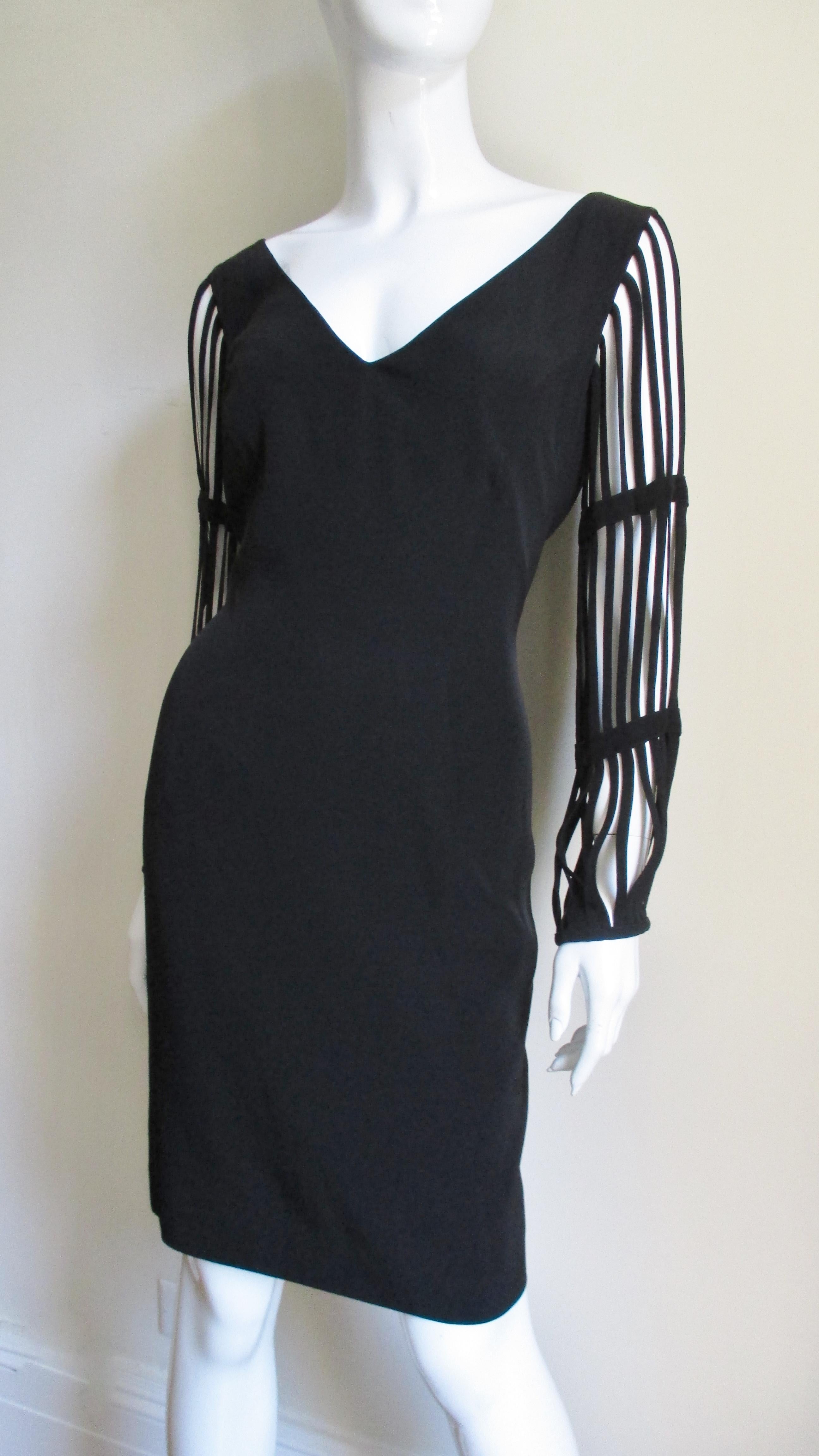 A great little black dress from Sophie Sitbon, Paris.  It is a simple V neck semi fitted dress with great cage sleeves comprised of finished strips of arm length fabric.  The effect is fabulous.  It is fully lined with a center back zipper.
Fits