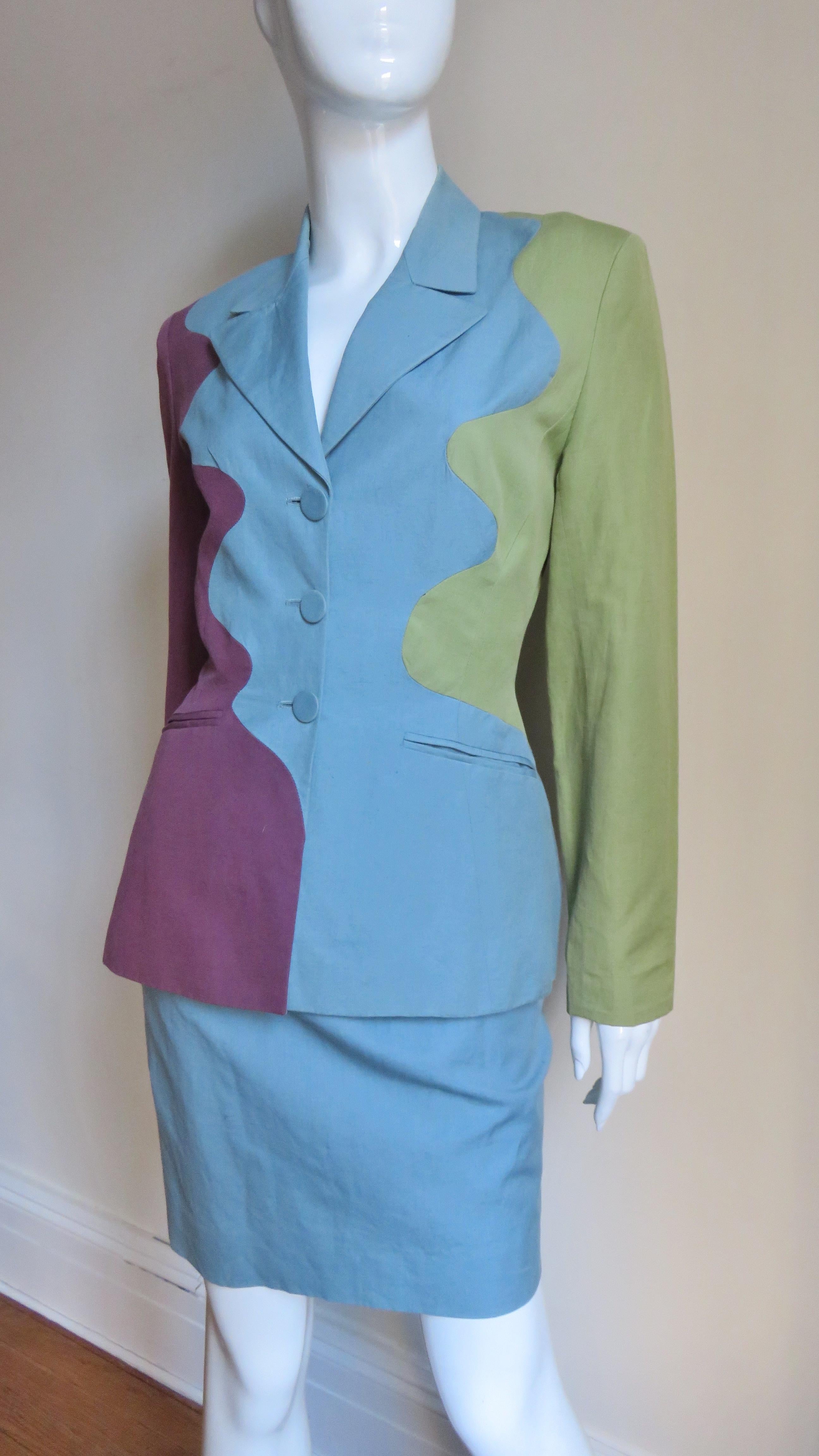 A pretty linen cotton linen blend skirt suit from Sophie Sitbon in blue, green and burgundy. The jacket has a lapel collar, welt hip pockets, small shoulder pads and button front and cuffs.  It is divided into the three wavy vertical panels each a