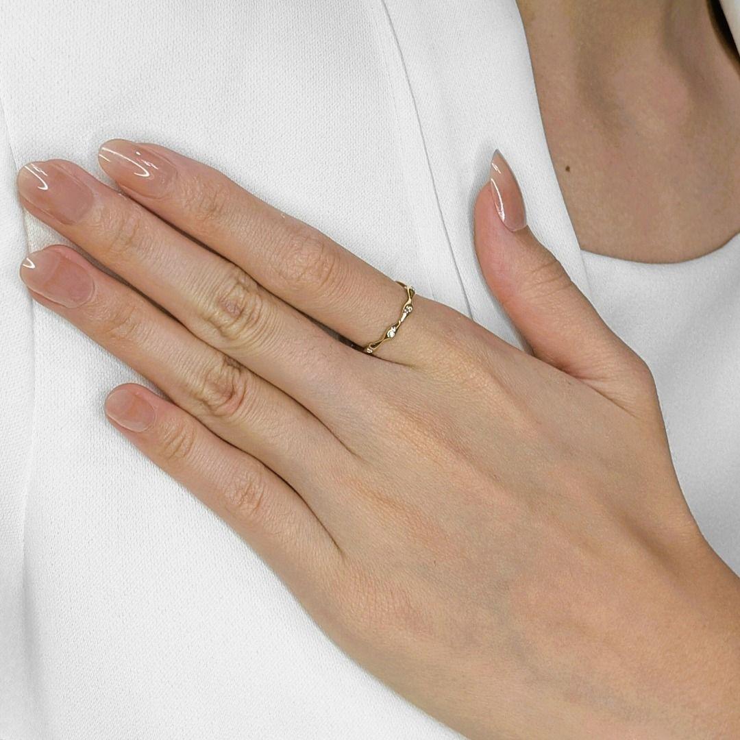 Imagina un susurro de brillo sutil, una delicada banda de oro amarillo de 14 quilates adornando suavemente tu dedo. Este anillo de segunda mano presenta cinco pequeños diamantes brillantes redondos, con un total de 0,05 ct, de color H y claridad VS,