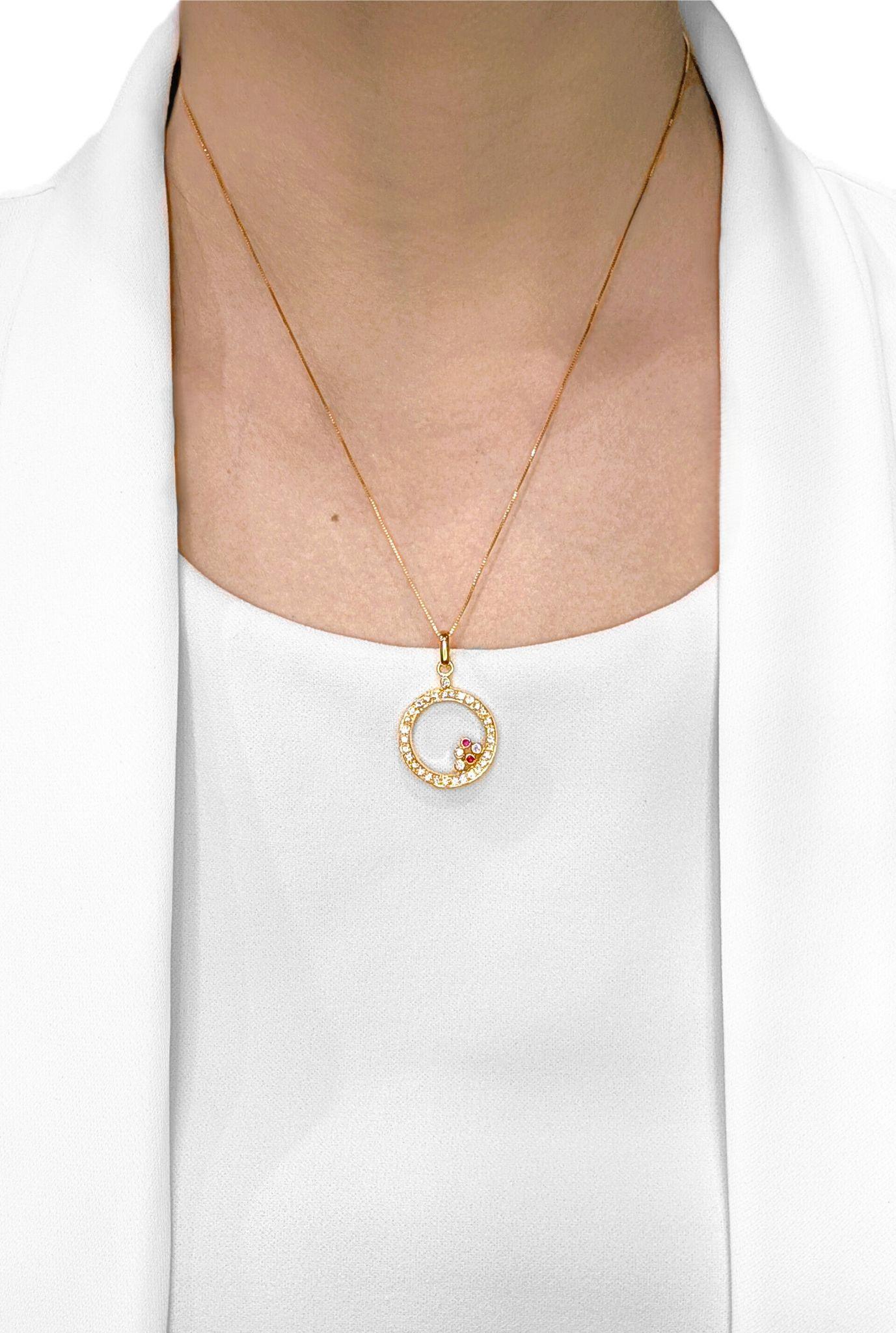 Découvrez une touche de sophistication vibrante avec ce pendentif neuf, non porté, méticuleusement réalisé en or jaune 18 carats rayonnant. Ce design circulaire captivant présente une délicate grappe de deux rubis ronds naturels brillants, d'une