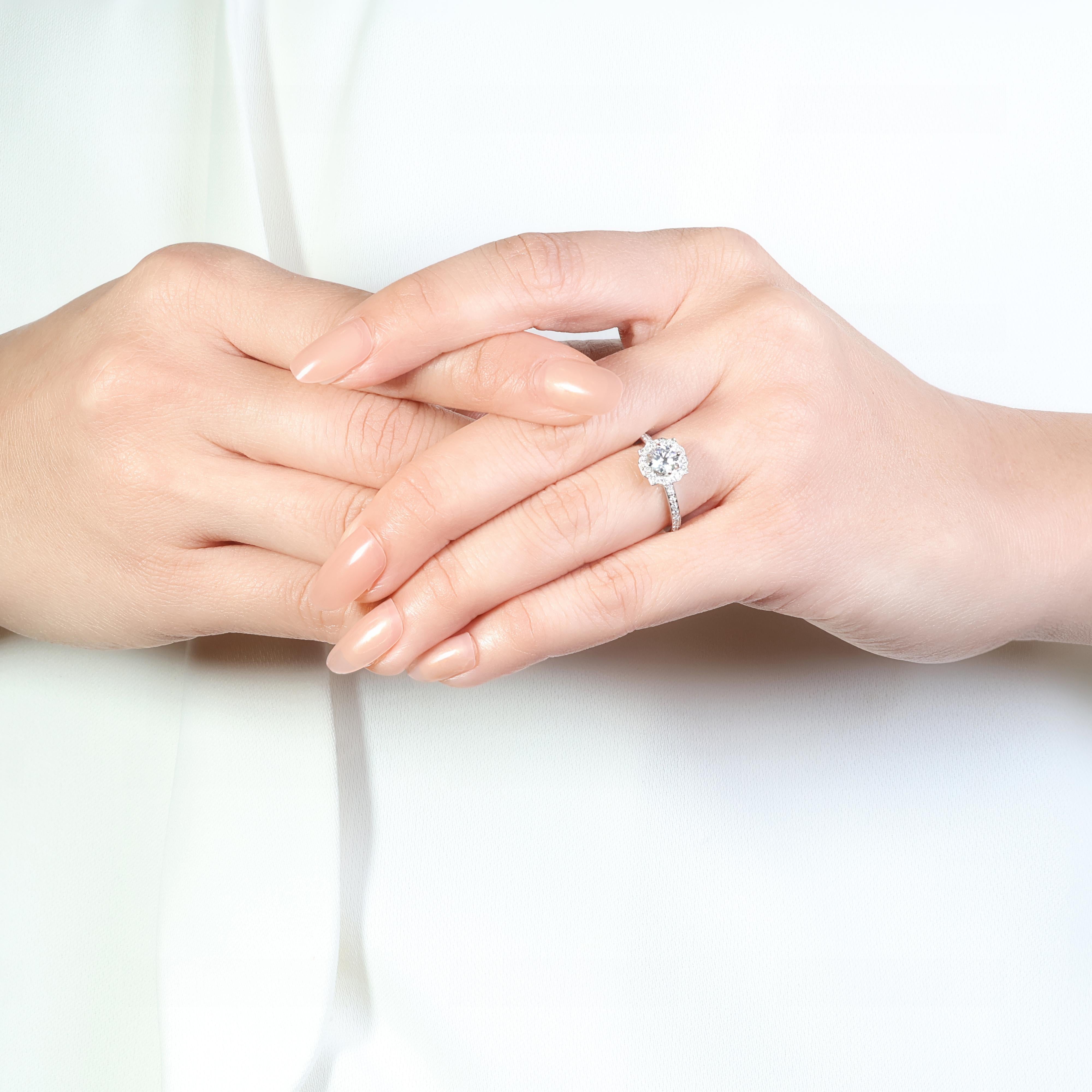 This exquisite 18K white gold ring features a dazzling 0.54-carat round brilliant center diamond, surrounded by a halo of 64 smaller round brilliant diamonds, totaling 0.38 carats. The ring boasts a G color and VS clarity for both the center and