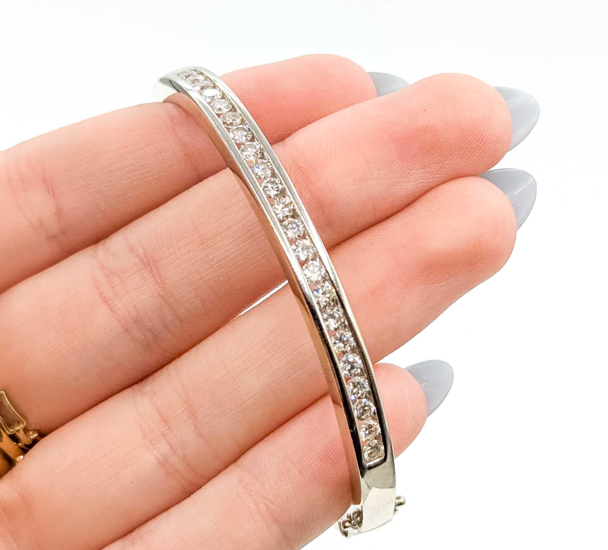 This timeless hinged bangle bracelet is crafted in 14k white gold and set with a continuous line of channel-set round brilliant diamonds. With a total carat weight of approximately 1.50 carats, the diamonds sparkle beautifully against the sleek