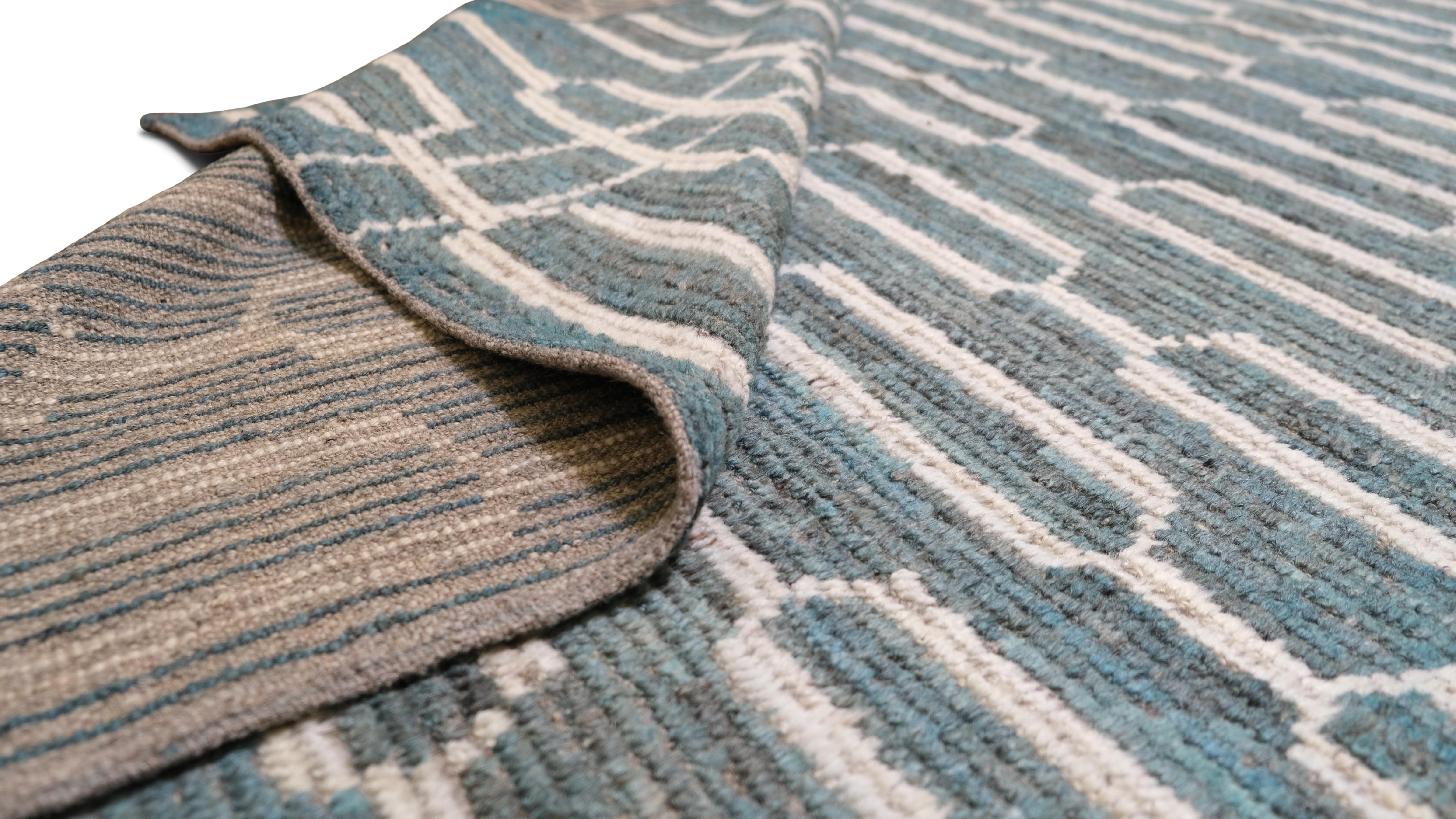 Dieser atemberaubende, handgeknüpfte Wollteppich mit seinem modernen, geometrischen Design in einer harmonischen blaugrünen Farbpalette wertet Ihre Einrichtung auf. Das verschlungene Muster aus miteinander verbundenen Formen bietet eine frische und