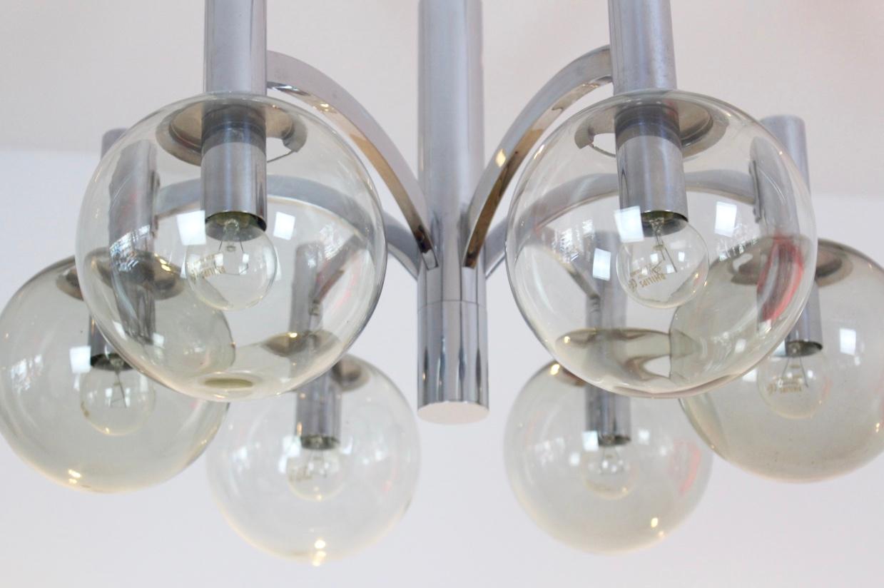 This sophisticated chrome chandelier of the 1960s is made by Kaiser Leuchten, Germany. It has a classic look with a nice Geometric structure: it is pure, simple and it gives a beautiful light with 6 glass bulbs on a chromed frame. This chandelier is
