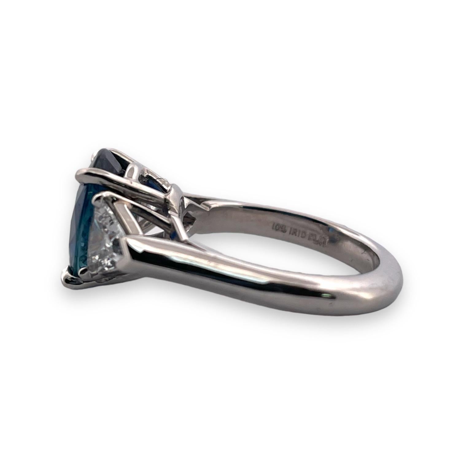 Unveil the splendor of a 3.64 carat Cylon sapphire, heat-treated to enhance its deep blue allure, flanked by 1.20 carat of immaculate trillion cut diamonds. This size 5.75 platinum ring, celebrating the pinnacle of luxury with D color and SI quality