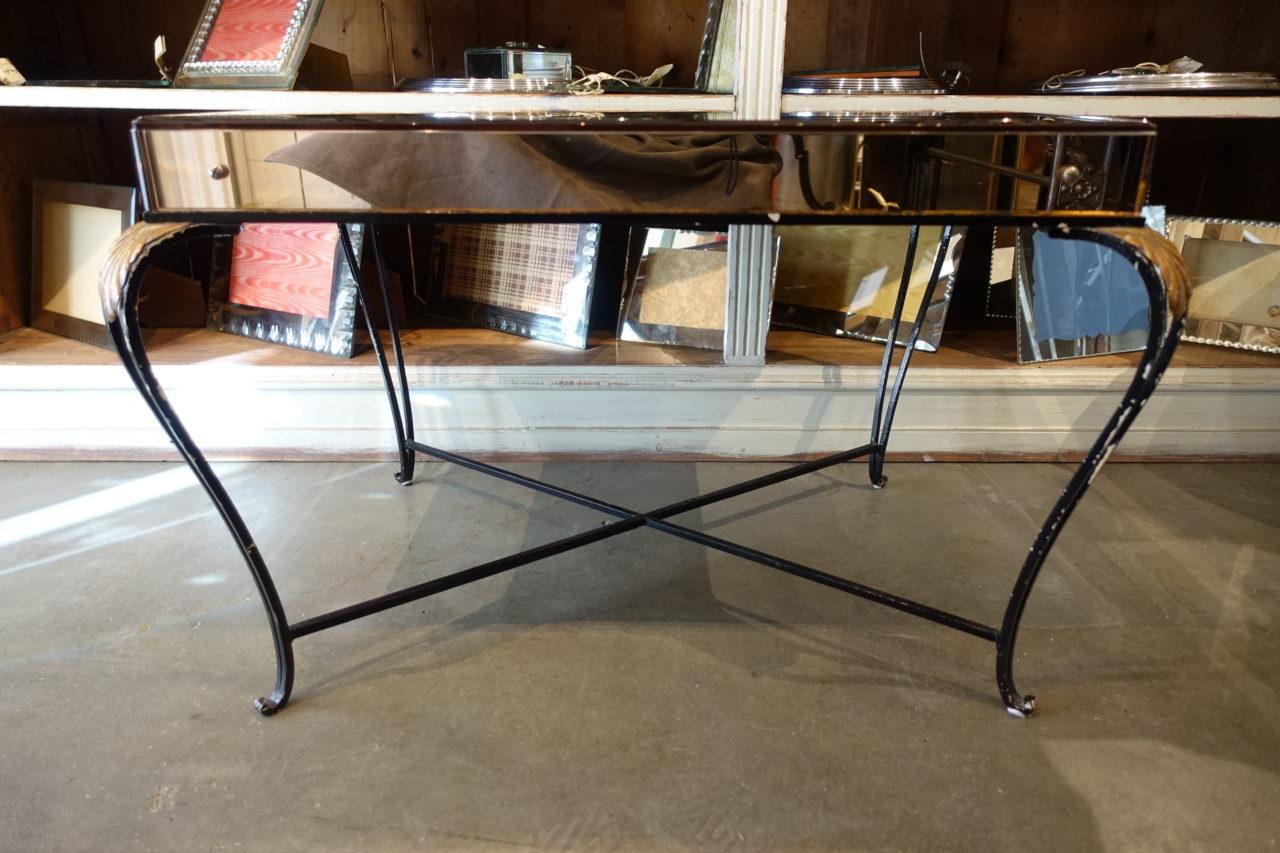 Gorgeous vintage mirrored table, from circa 1940s France. Elegant cast iron legs, with lovely gilt iron leaves at each corner. Stunning smoky mirrored glass along the border.