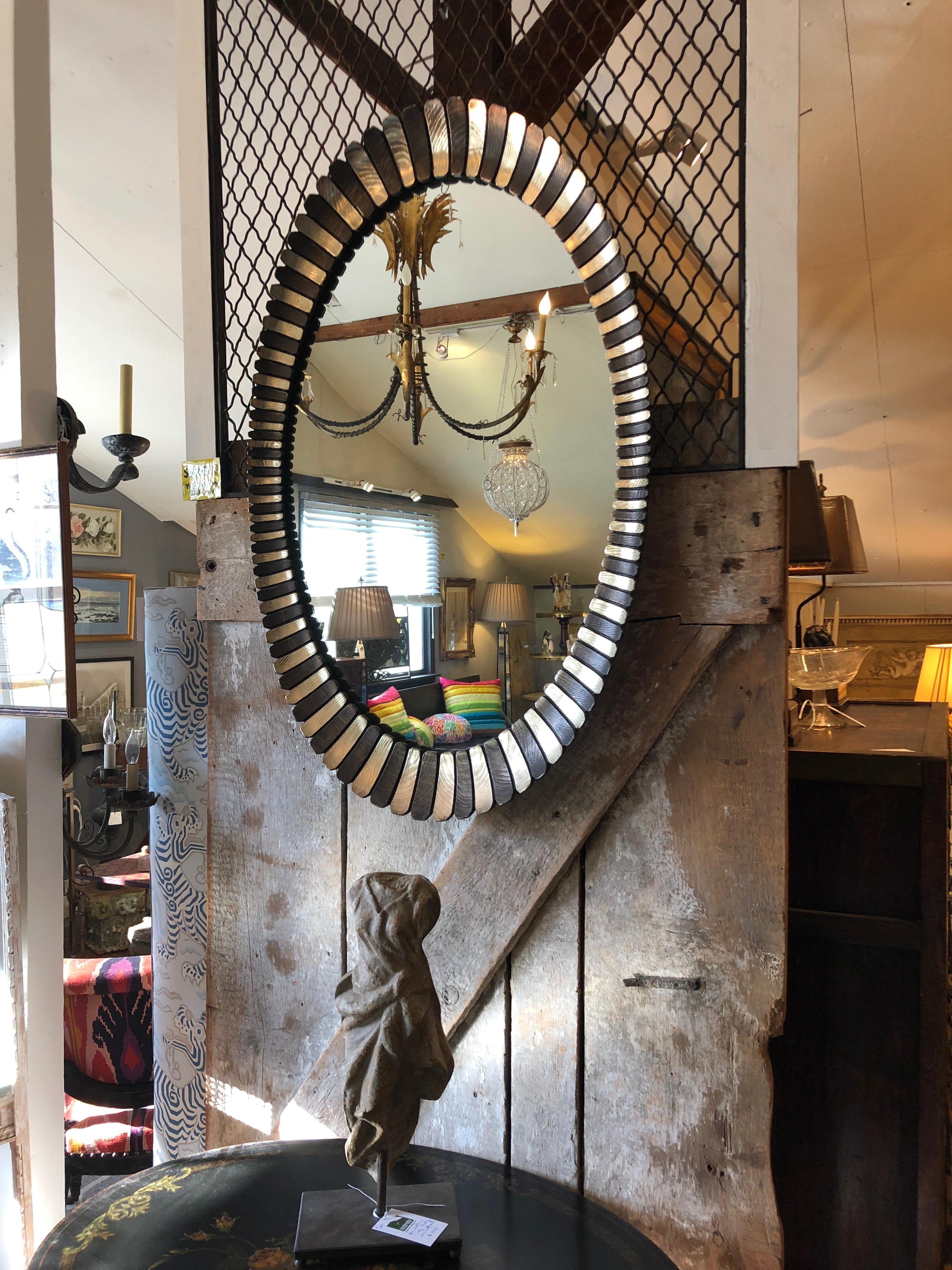 An eye-catching large oval mirror having alternating sunbursty slats in gilded gold and bronze.