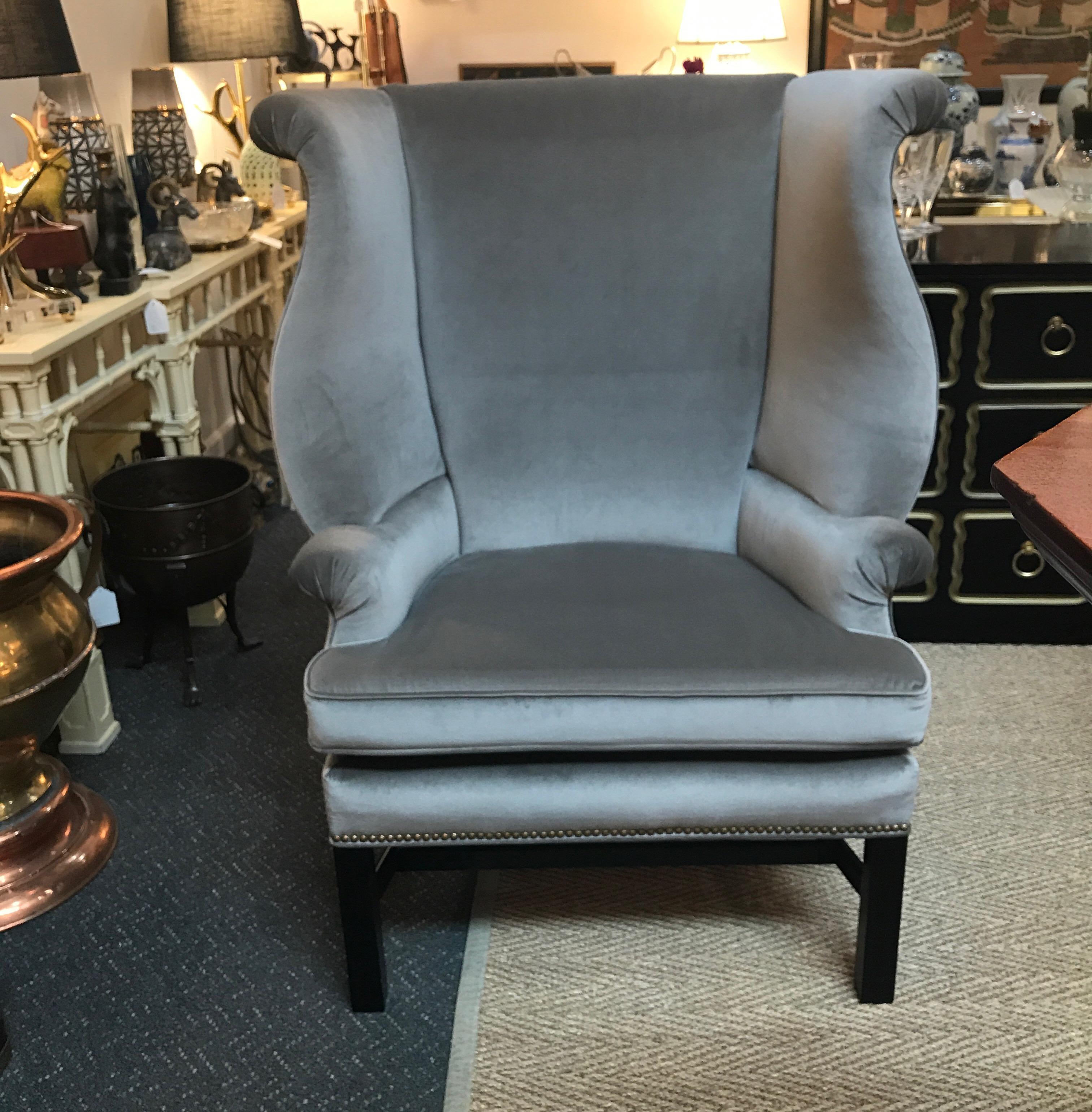 A shapely and large wing chair by Baker Furniture, the premier American maker. The rounded back with shapely sides and arms with reversible seat cushion resting on four straight Chippendale ebonized legs. Newly covered in grey velvet with antiqued
