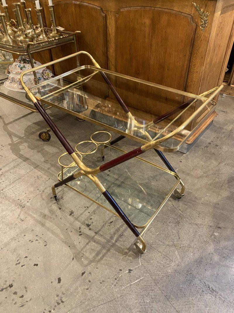 Super handsome Italian bar cart/ serving trolley designed by Cesare Lacca in the 1950s.

The stylish piece has an X-shaped brass frame with gorgeous mahogany-stained beech wood and elegant wheels, as well as a bottle holder.
       