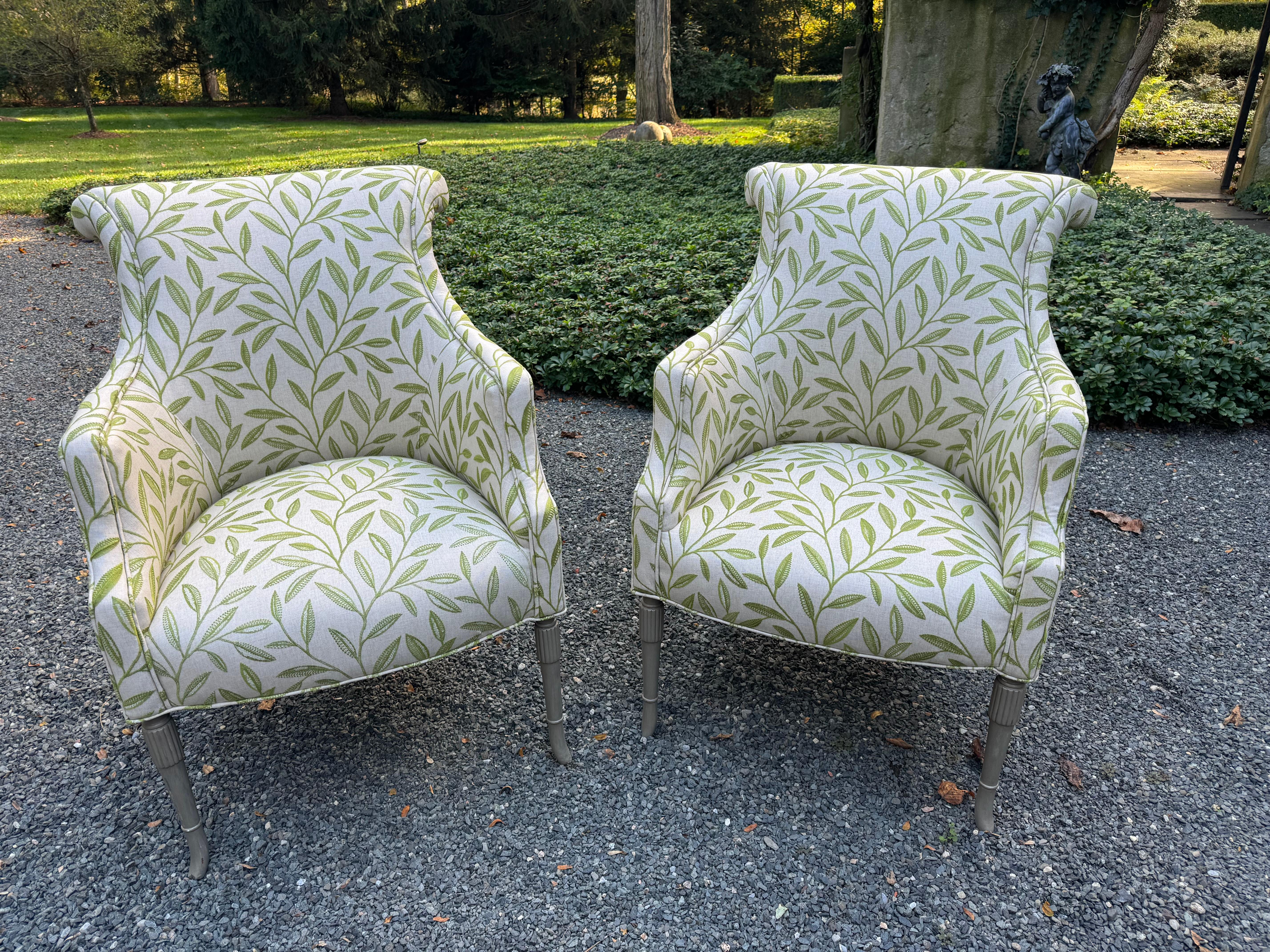 Sophisticated pair of nicely carved and upholstered club chairs having grayish beige background with fresh contemporary springy green leaf pattern.  Legs are carved and a lovely painted putty color.   Chairs feature beautifully shaped arms and a