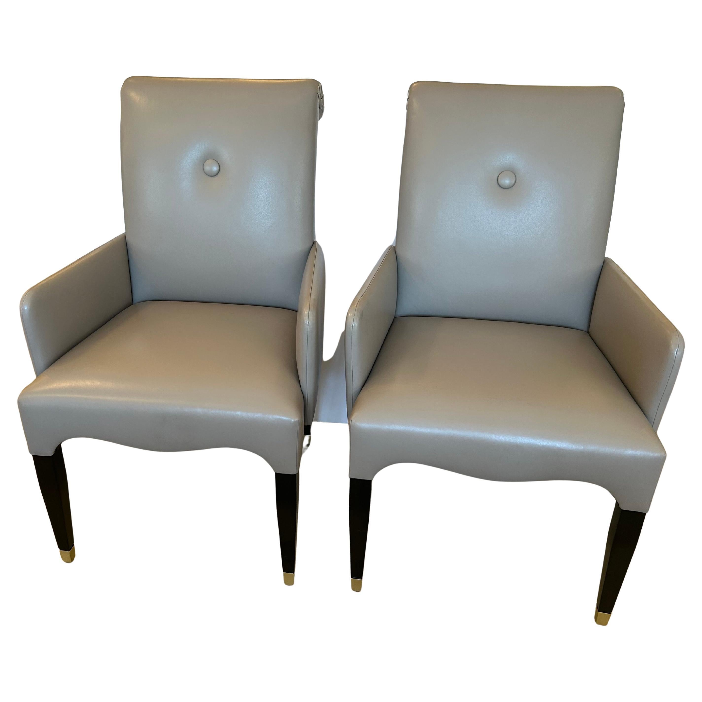 Stunning pair of custom taupe leather club chairs having tailored elegance and tapered ebonized legs terminating in silver leaf feet.
Seat depth 19
Arm height 25