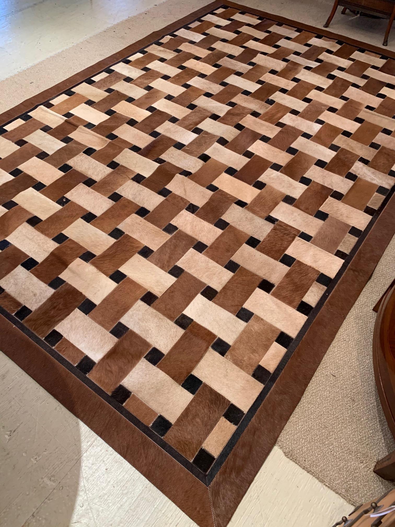 A great looking cowhide area rug in brown, cream and black that has a woven or patchwork geometric design.
  