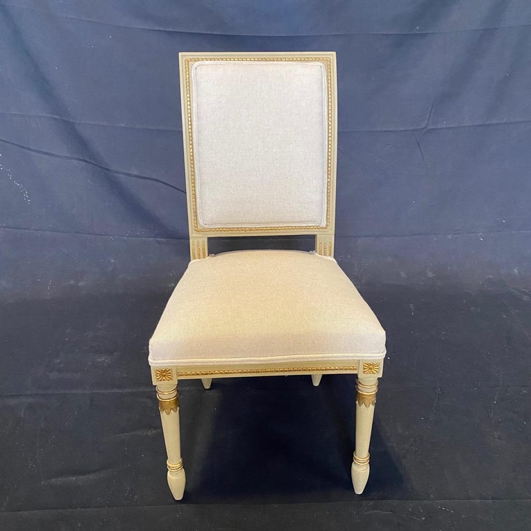 Set of 4 French Louis XVI style chairs having an elegant silhouette and a carved wooden frame newly upholstered in a high quality British cotton linen neutral fabric. The chairs have a square backrest and seat carved with classic details. The gold