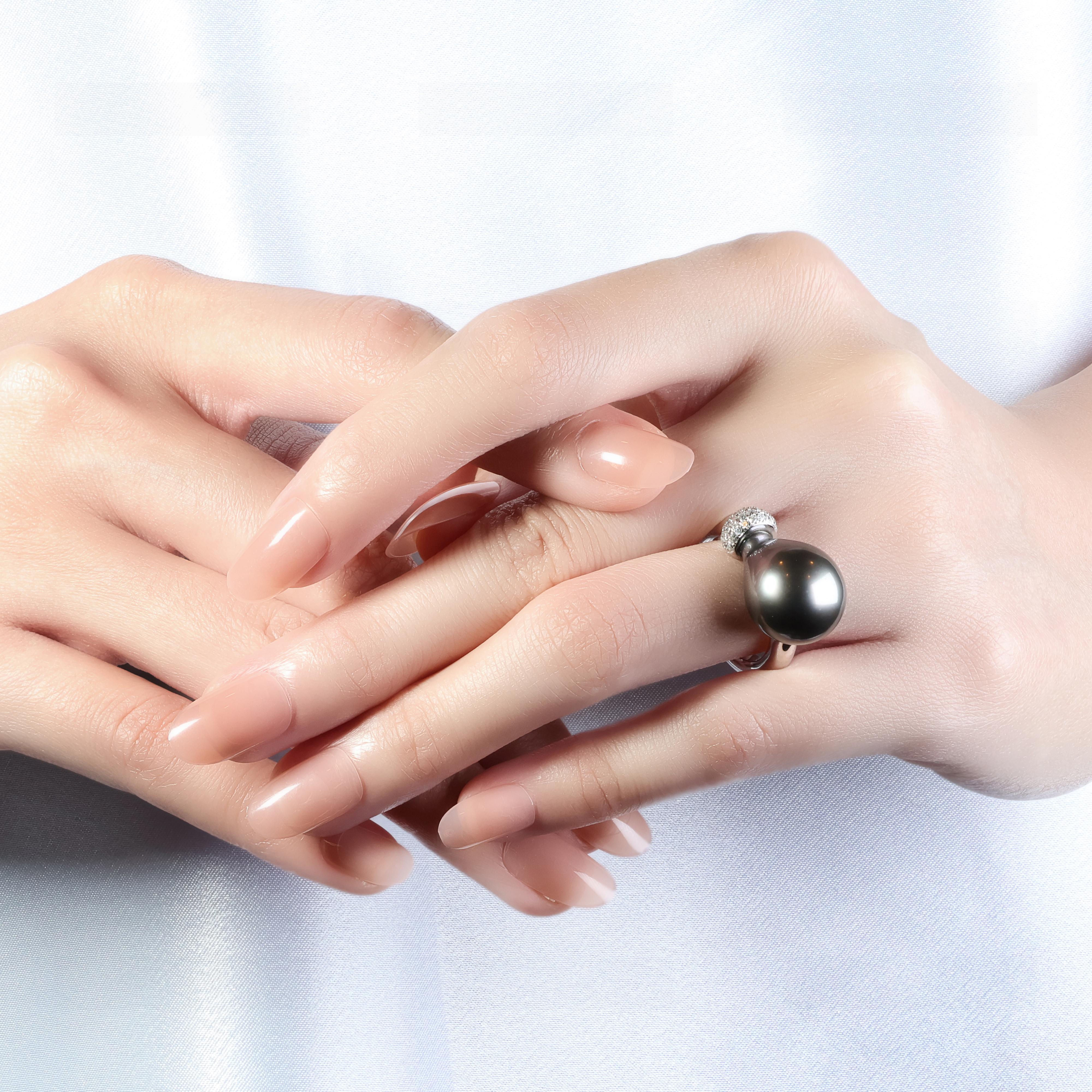 This stunning 18K white gold ring features a captivating Tahitian pearl as the centrepiece, showcasing a beautiful grey hue. The ring is adorned with 30 round brilliant diamonds, with a total carat weight of 0.60ct, boasting an impressive F colour