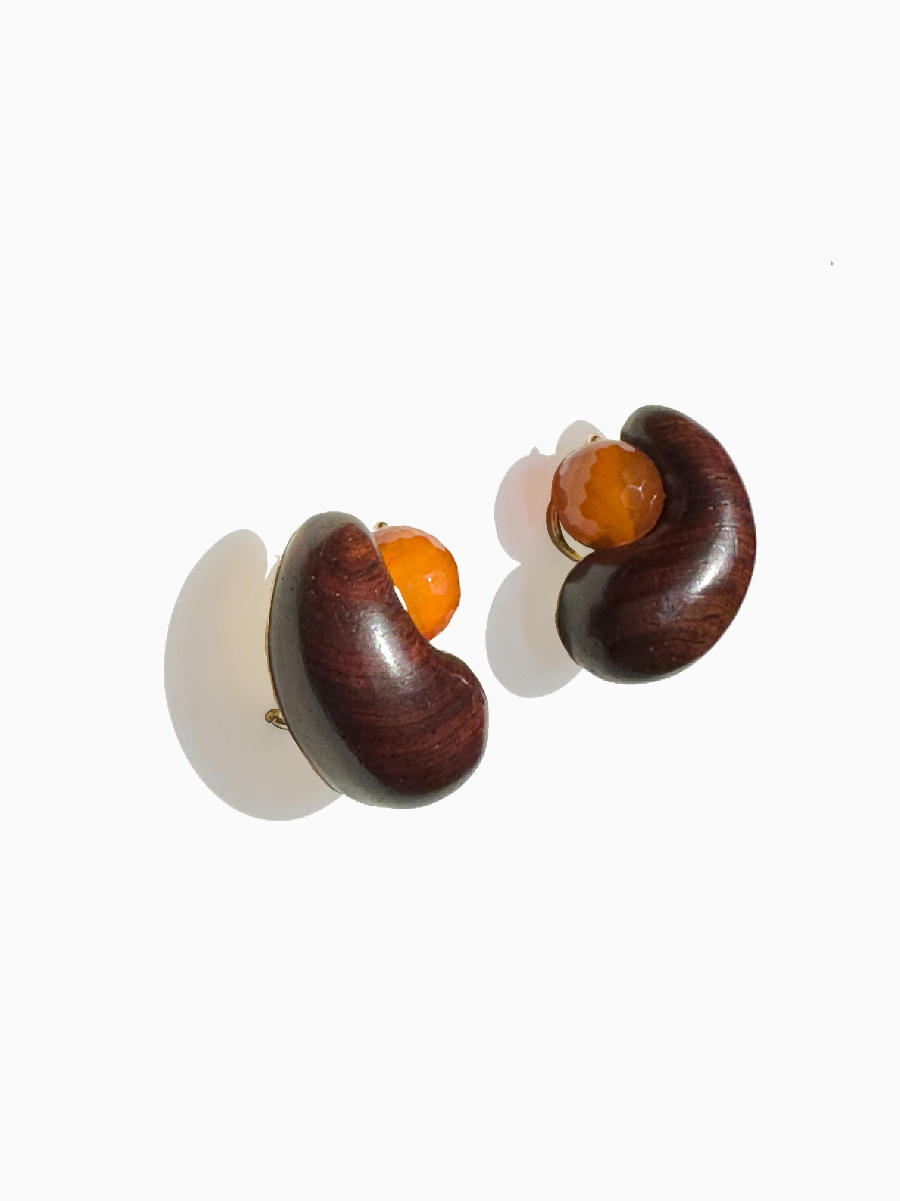 Clip-on gold backed Rosewood Cashew Earrings with a 12mm faceted Carnelian bead center. Set in 18 karat yellow gold , signed Sorab & Roshi. 
1.25