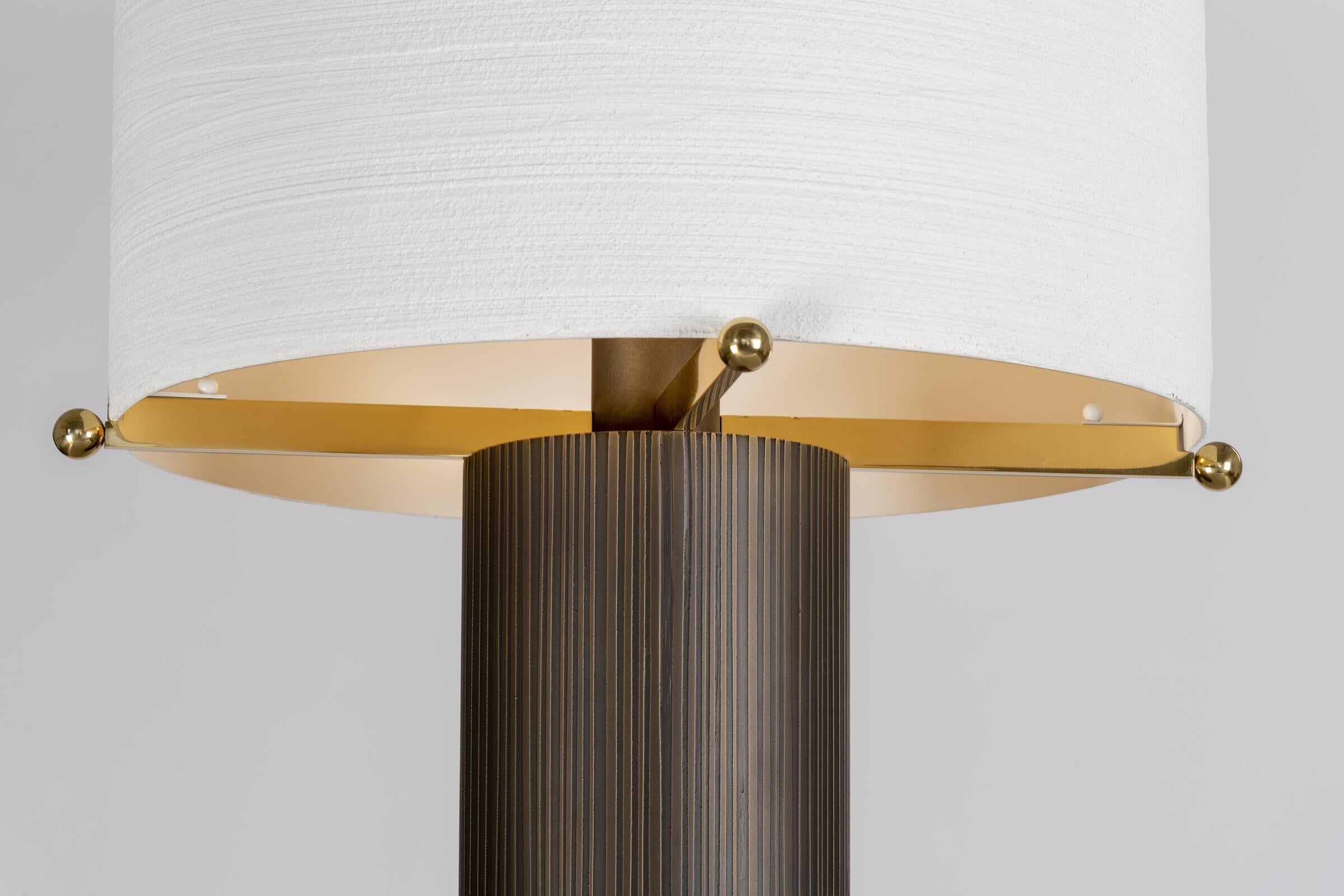 With a sleek cylindrical shaft and shade in contrasting textures, the Sorbet Table Lamp adds majestic scale and showcases the beauty of unique materials and hand-finished details. It is available in a bronze or green textured plaster base.
