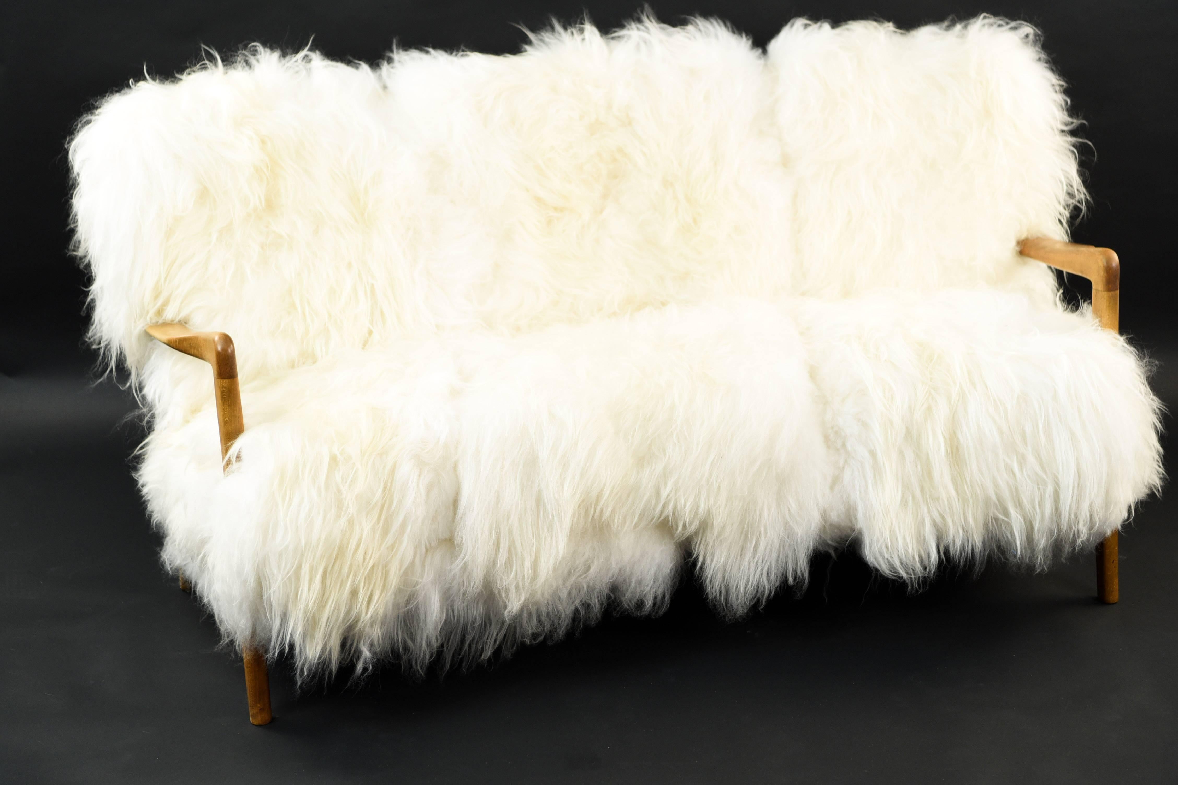 This sofa designed by Soren Hansen for Fritz Hansen is part of the 8000 series from the 1940s. It has been upholstered in luxurious, fluffy Mongolian lamb's fur, leaving just the recognizable armrests and legs exposed. An absolutely stunning piece