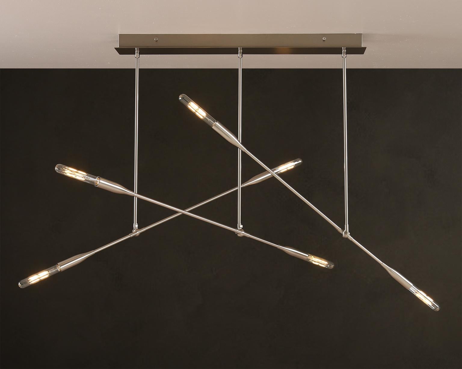 Trois lampes Sorenthia créent des angles spectaculaires sur un dais rectangulaire conçu à la main.  Ce lustre d'inspiration du milieu du siècle présente des ampoules apparentes, des lignes audacieuses et un espace négatif spectaculaire. Les bras
