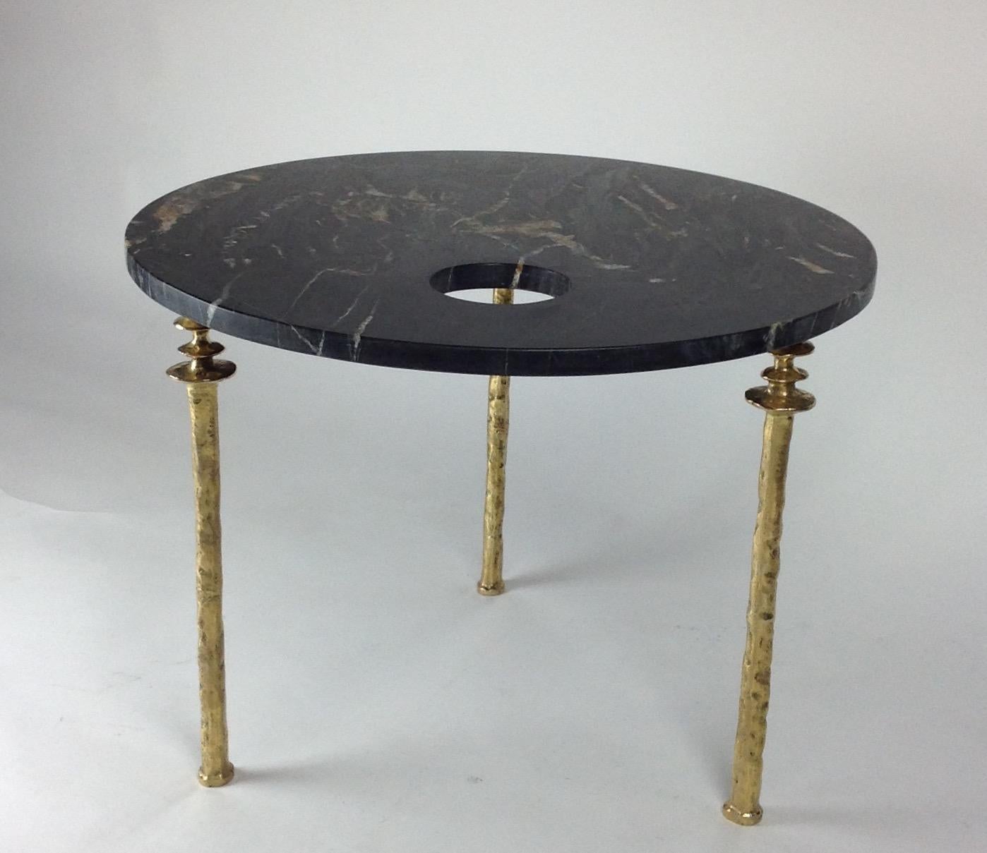 One marble-topped small scaled side tables. The round top has a single hole drilled off center in the black and gold marble top. The legs are cast silicon brass and have a unique organic texture.  This item is in our NYC showroom.  Custom models are
